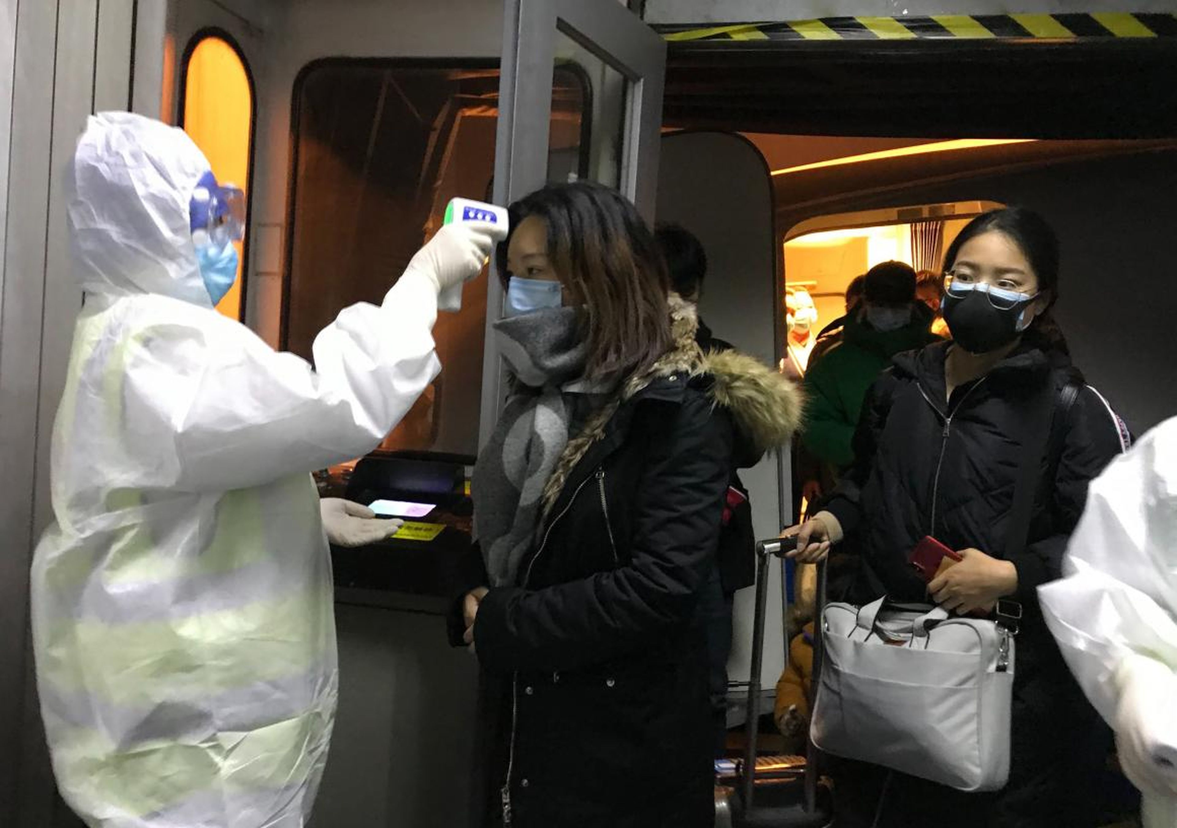 Oficiales sanitarios miden la temperatura corporal de los pasajeros que llegan de Wuhan, China, el 22 de enero de 2020, en el aeropuerto de Pekín..