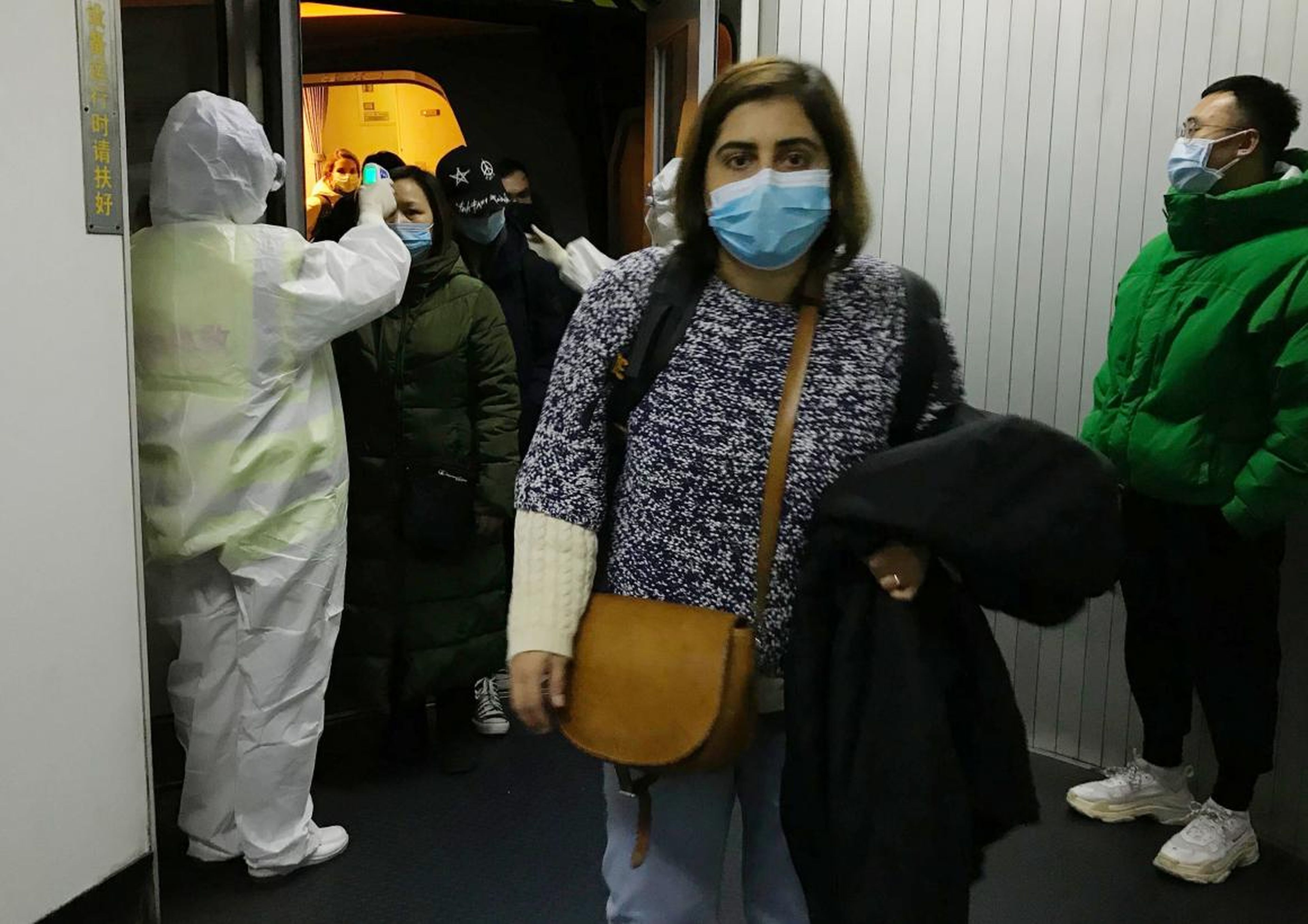 Personal sanitario con equipo de protección comprueba las temperaturas de los pasajeros que llegan al aeropuerto de Pekín desde Wuhan, China, el pasado miércoles.