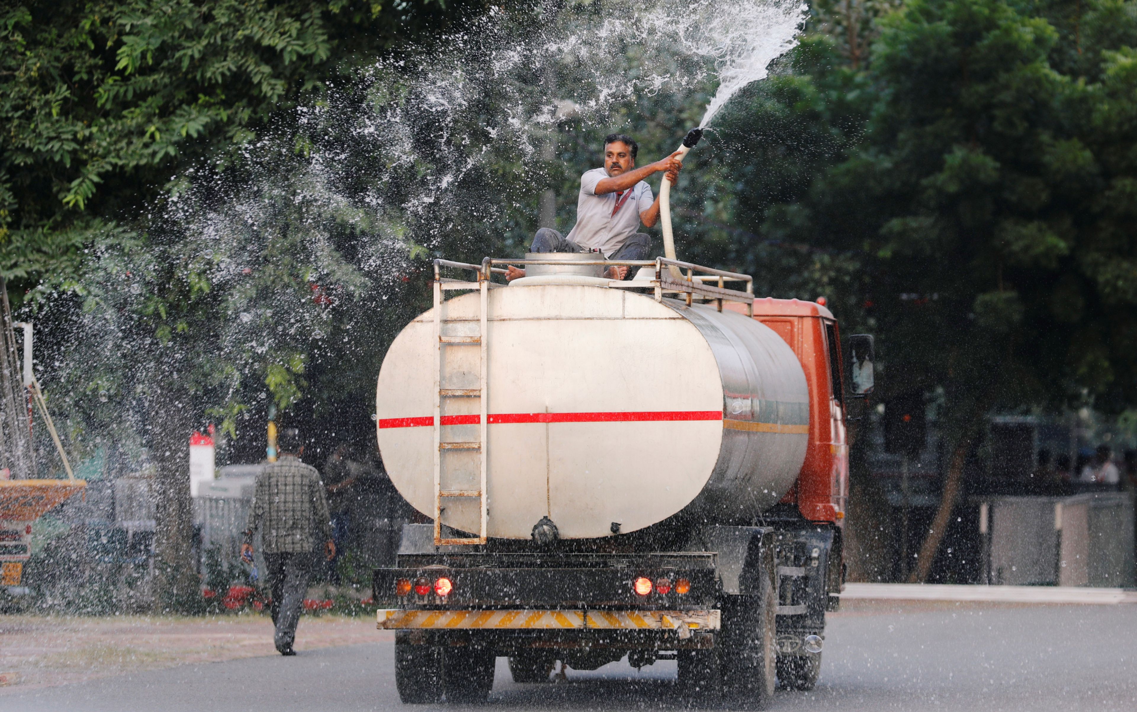 Un hombre rocía agua, mezclada con un reactivo ecológicamente seguro en Nueva Delhi