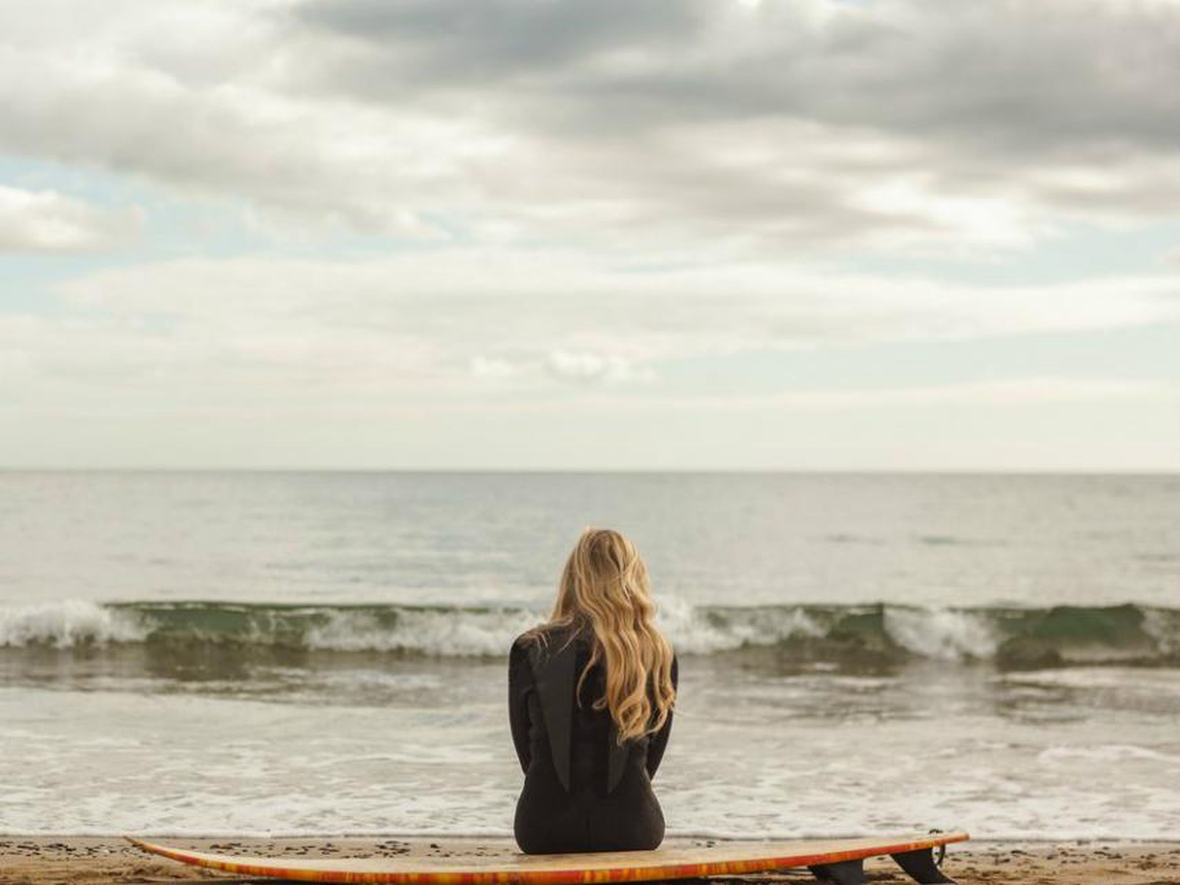 Una mujer surfista mirando al mar