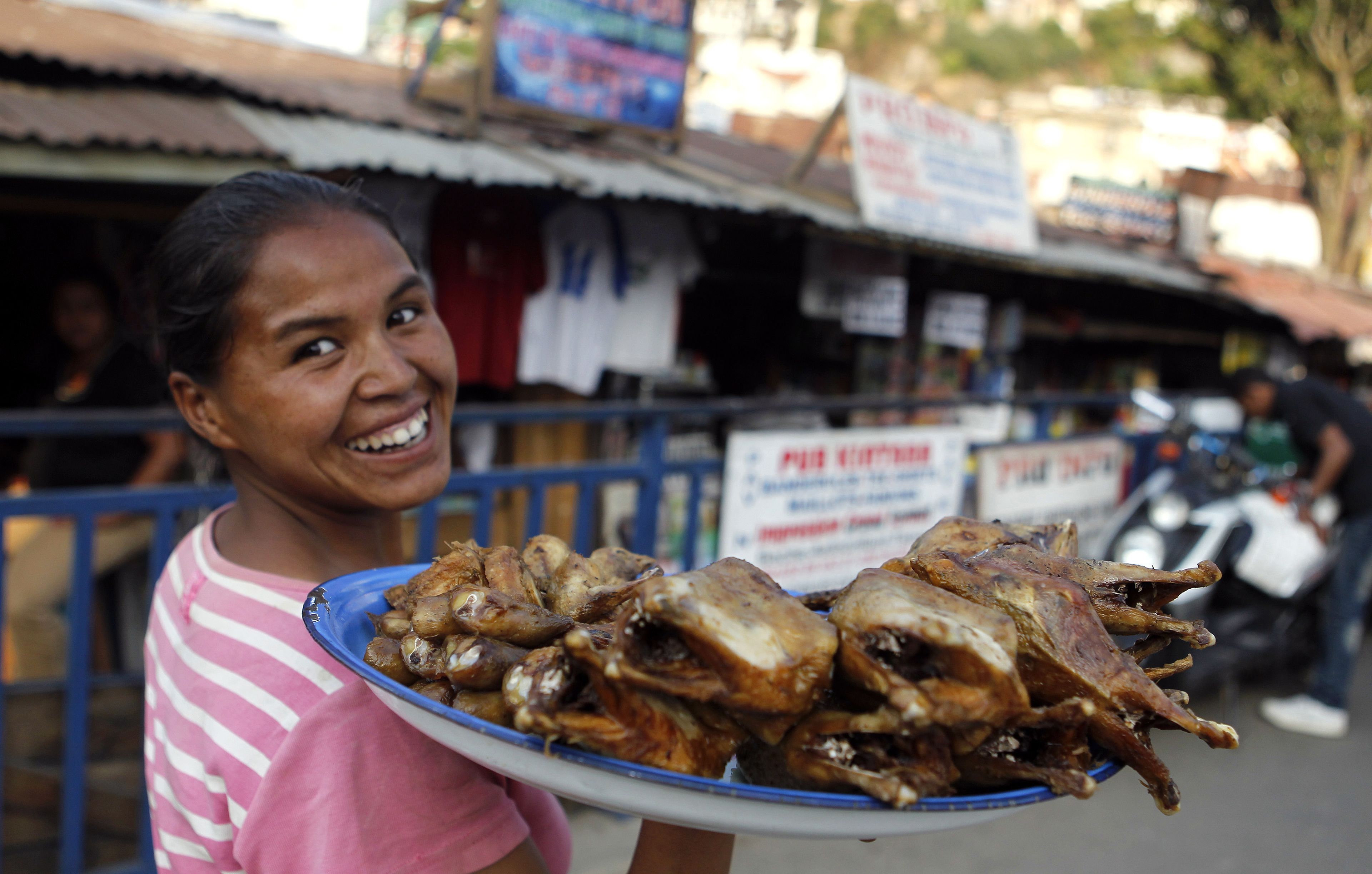 Una mujer vende pollo asado por las calles de Antananarivo, la capital de Madagascar.