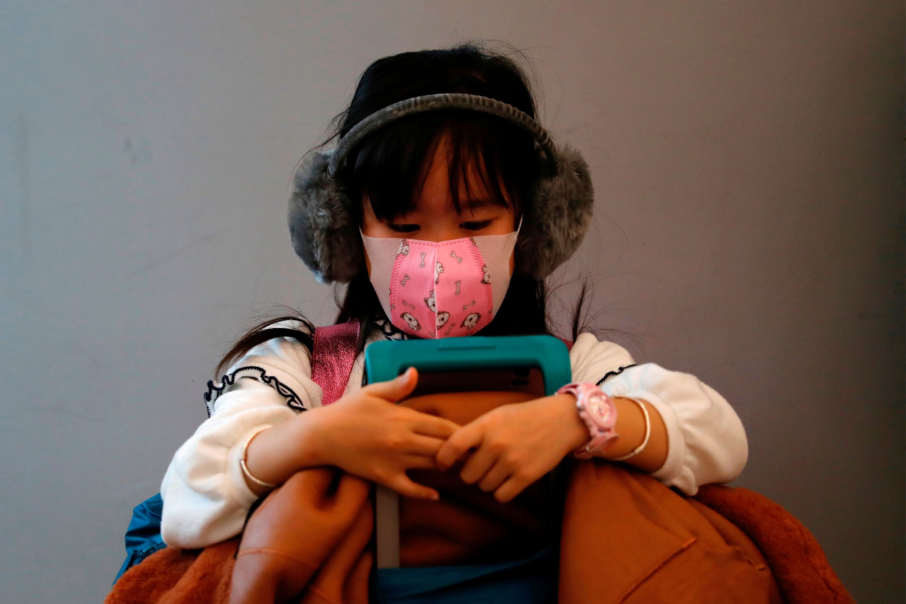 Una niña con mascarilla espera en una estación de Hong Kong