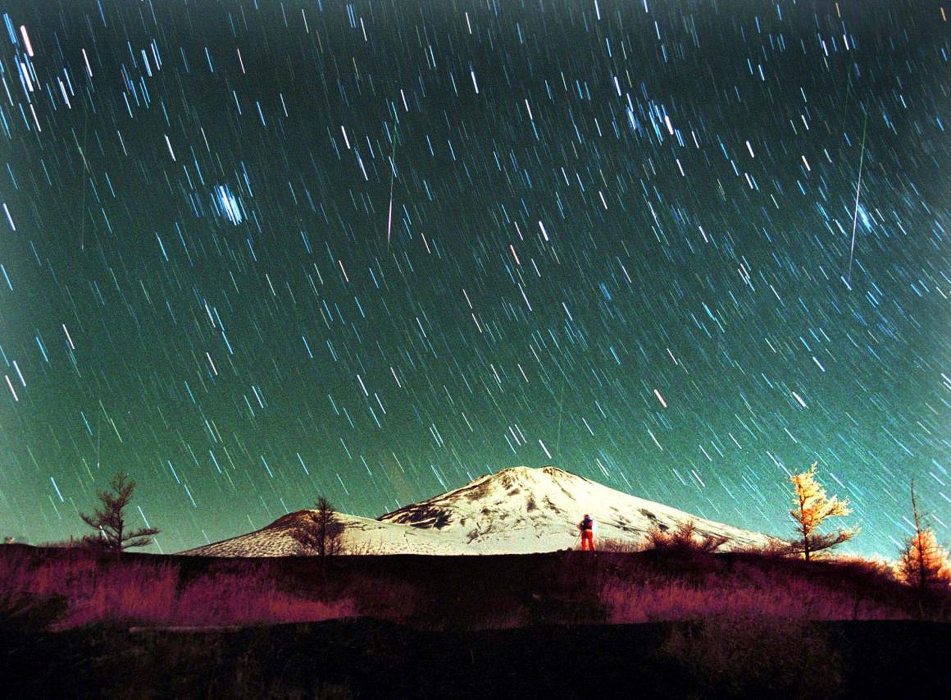 En esta foto de 7 minutos de exposición, sobre el nevado monte Fuji en Japón, el 19 de noviembre de 2001, se ven estrellas Leonidas por el cielo.