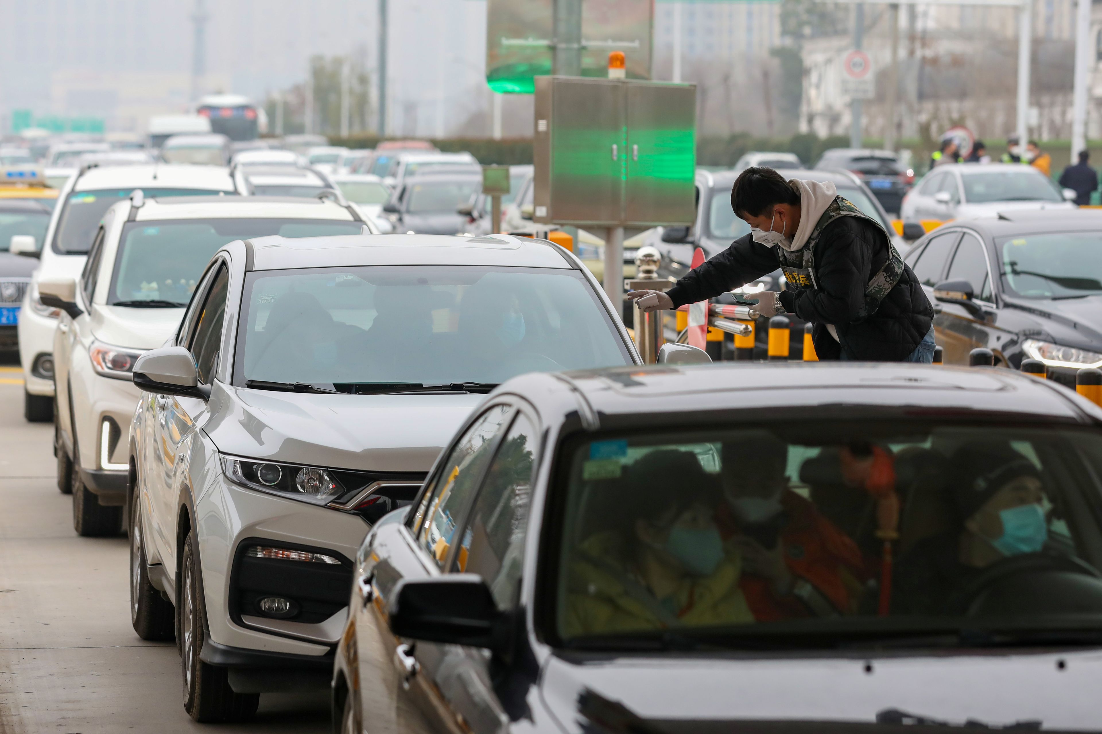 Un operario lleva a cabo controles térmicos a los conductores y pasajeros de vehículos en Wuhan, epicentro del coronavirus.