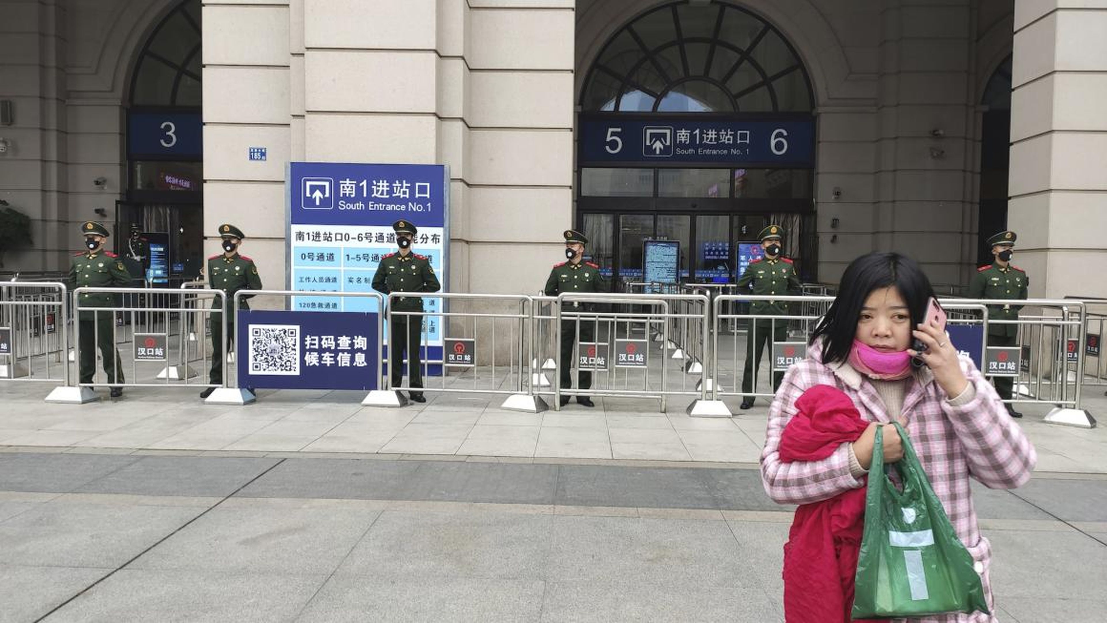 A woman talks on her cellphone as Chinese paramilitary police stand guard at an entrance to the closed Hankou Railway Station in Wuhan in central China's Hubei Province, Thursday, Jan. 23, 2020.