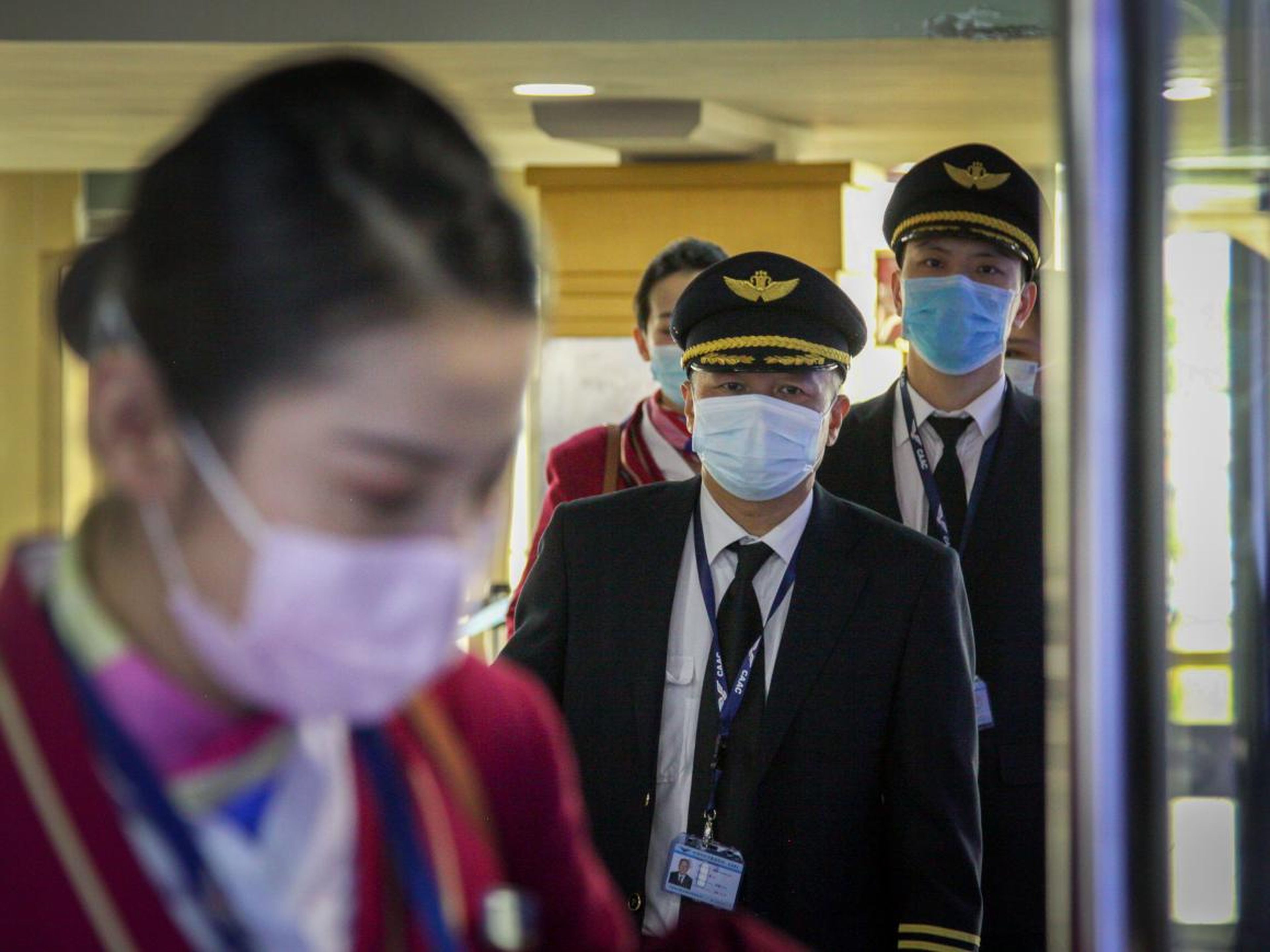 Los miembros de la tripulación de un vuelo de China Southern Airlines procedente de Changsha (China) portaban máscaras al pasar por un control de pasaportes a su llegada al aeropuerto Jomo Kenyatta de Nairobi (Kenya).