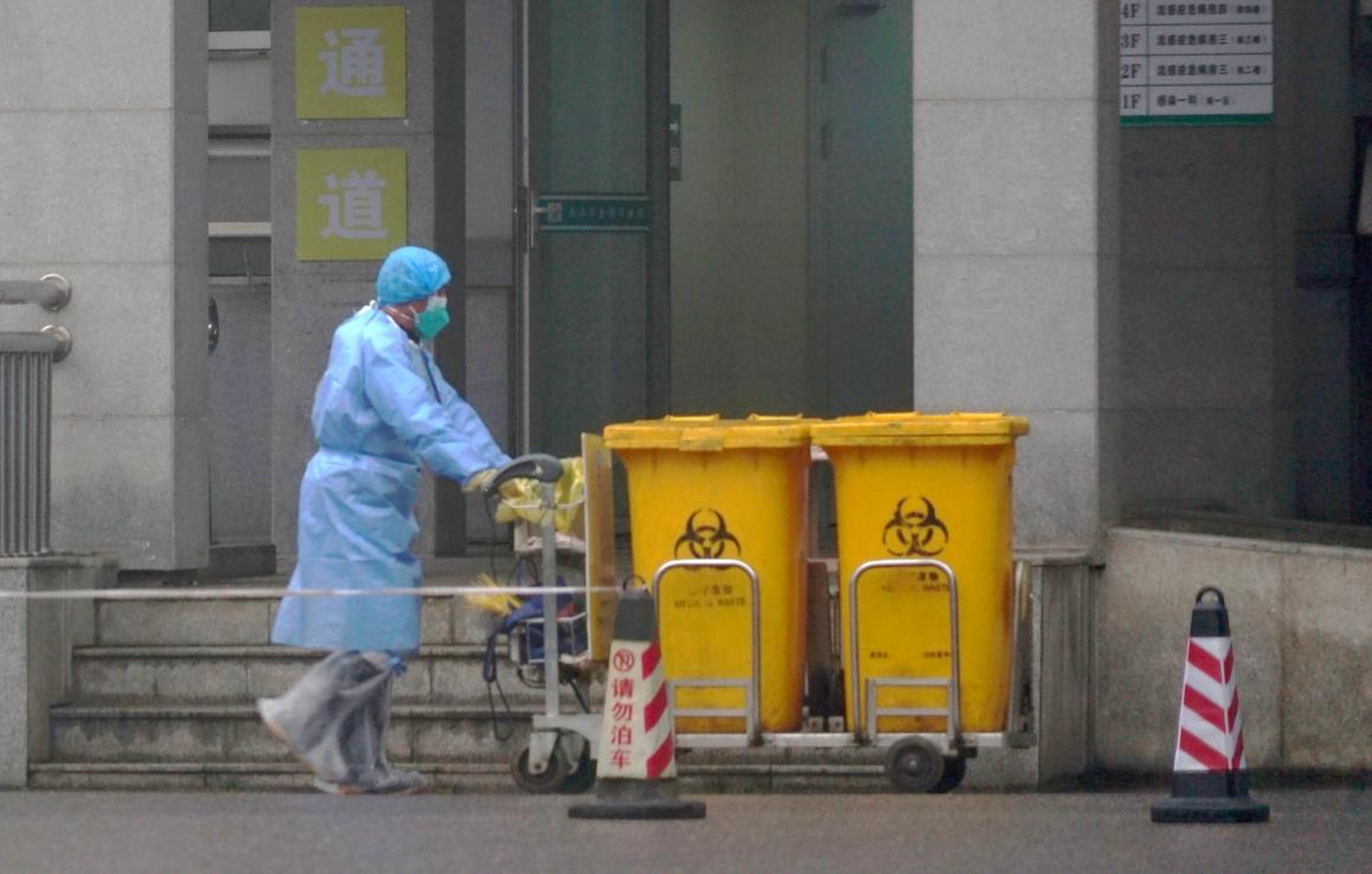 A staff member moves bio-waste containers past the entrance of the Wuhan Medical Treatment Center in Wuhan, China, where some people infected with a coronavirus were being treated on January 22, 2020.