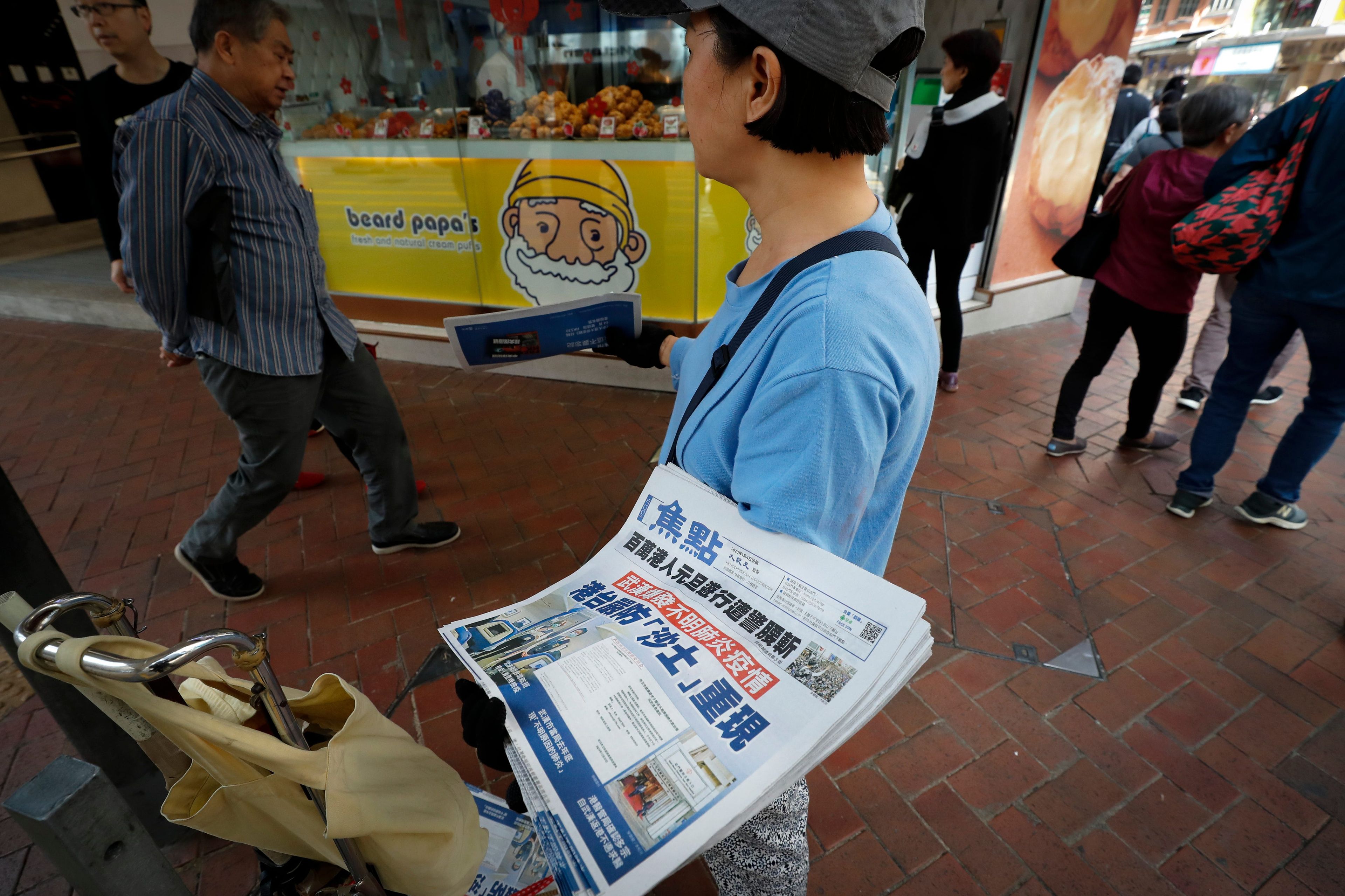 Un vendedor reparte copias de un periódico con titulares sobre el brote de coronavirus en Hong Kong el 11 de enero de 2020.