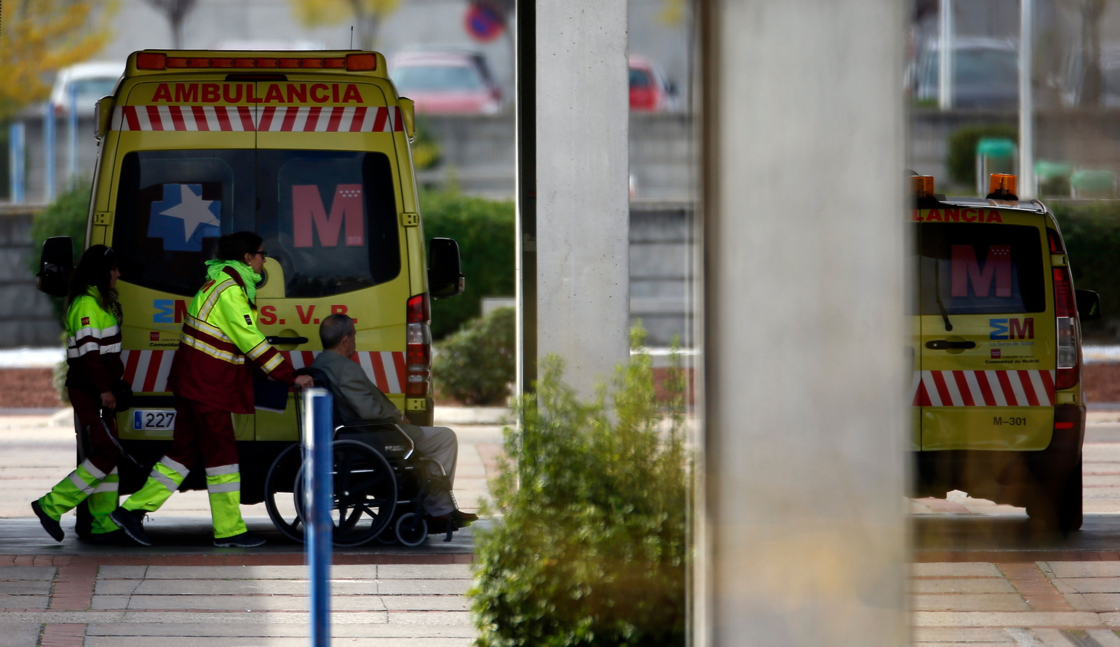 2 técnicos de ambulancias acompañan a un enfermo en silla de ruedas en el hospital de Alcorcón