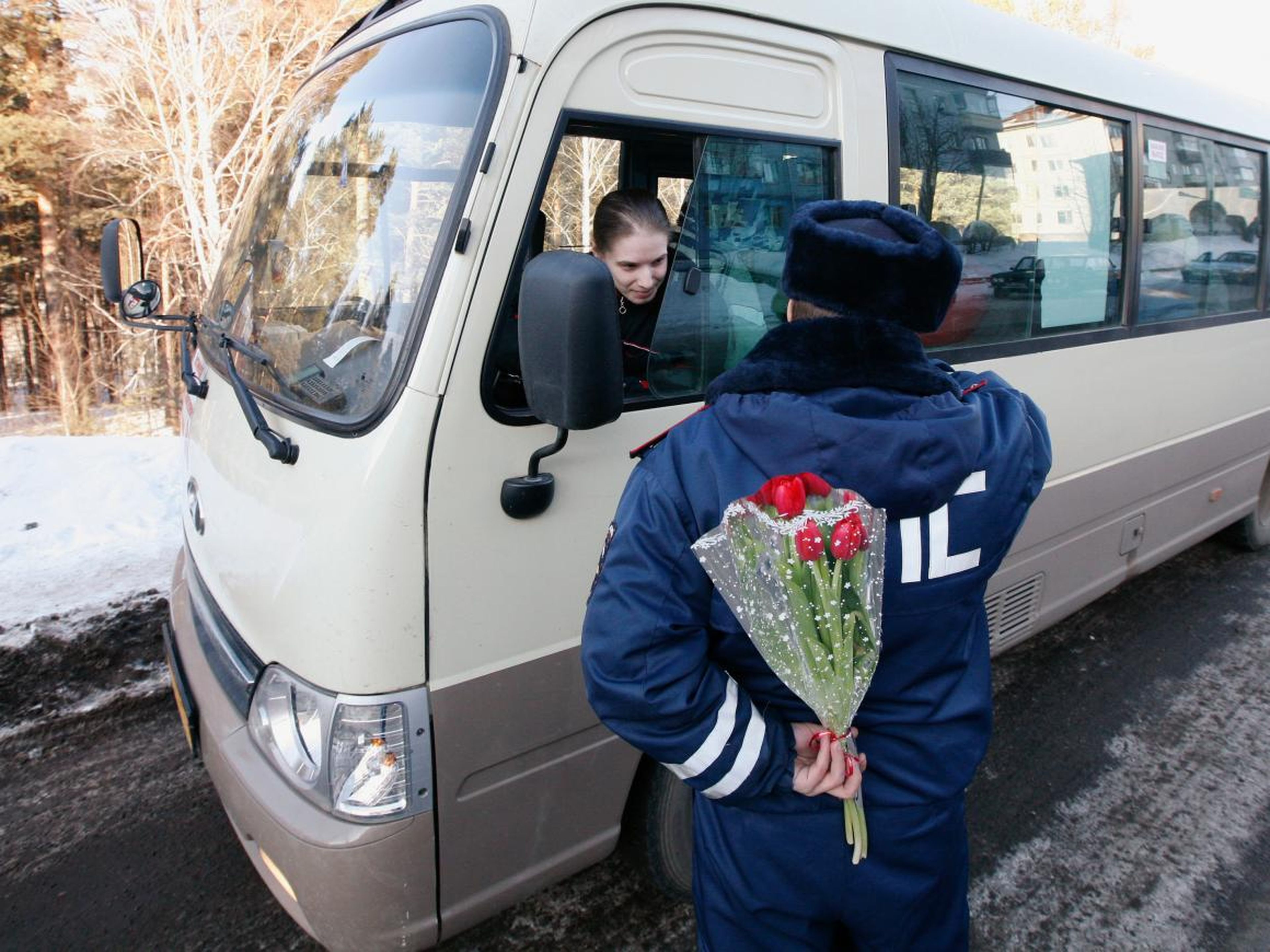Un policía de tránsito esconde un ramo de flores a sus espaldas cerca de Krasnoyarsk, Siberia.