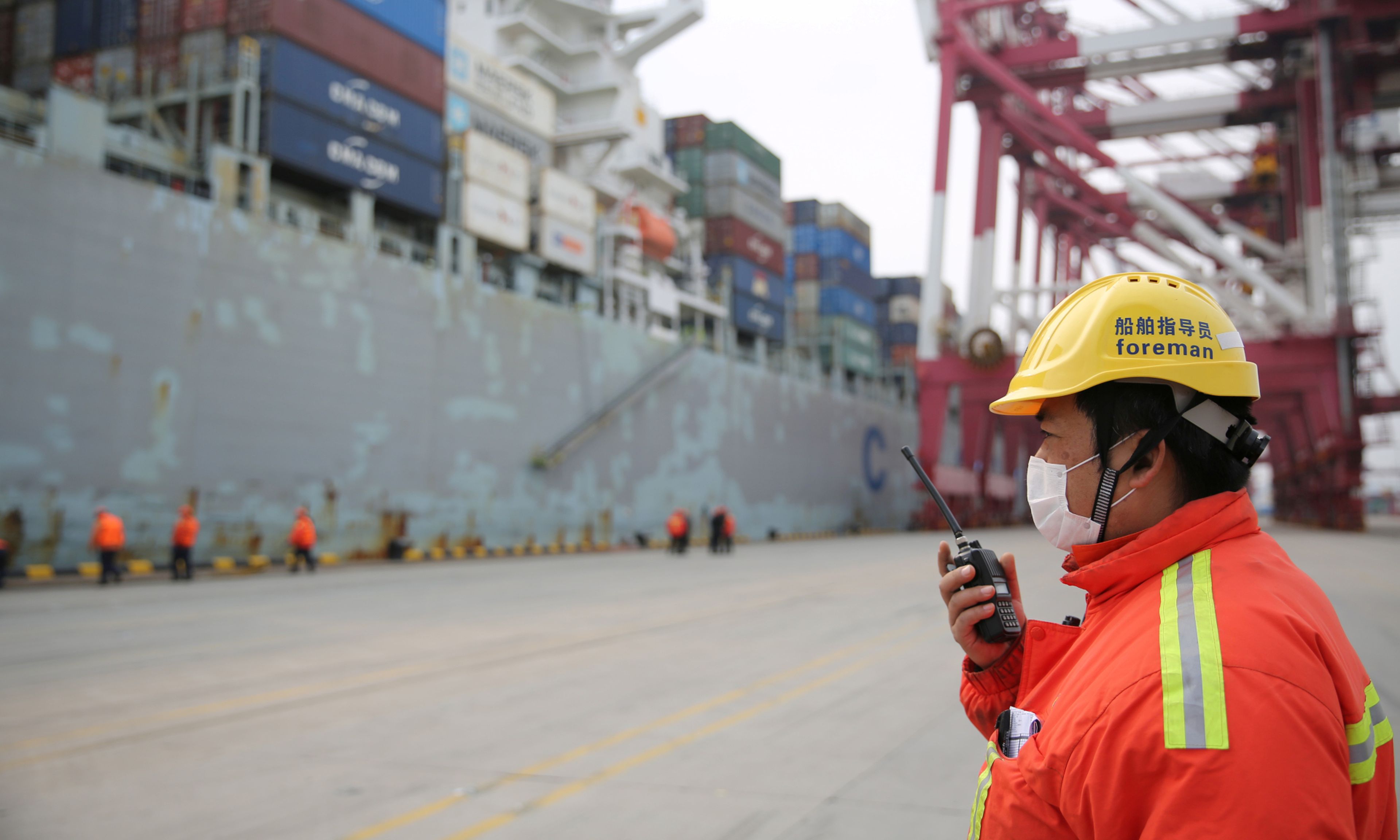 Un estibador controla la descarga de un carguero comercial en el puerto chino de Qingdao