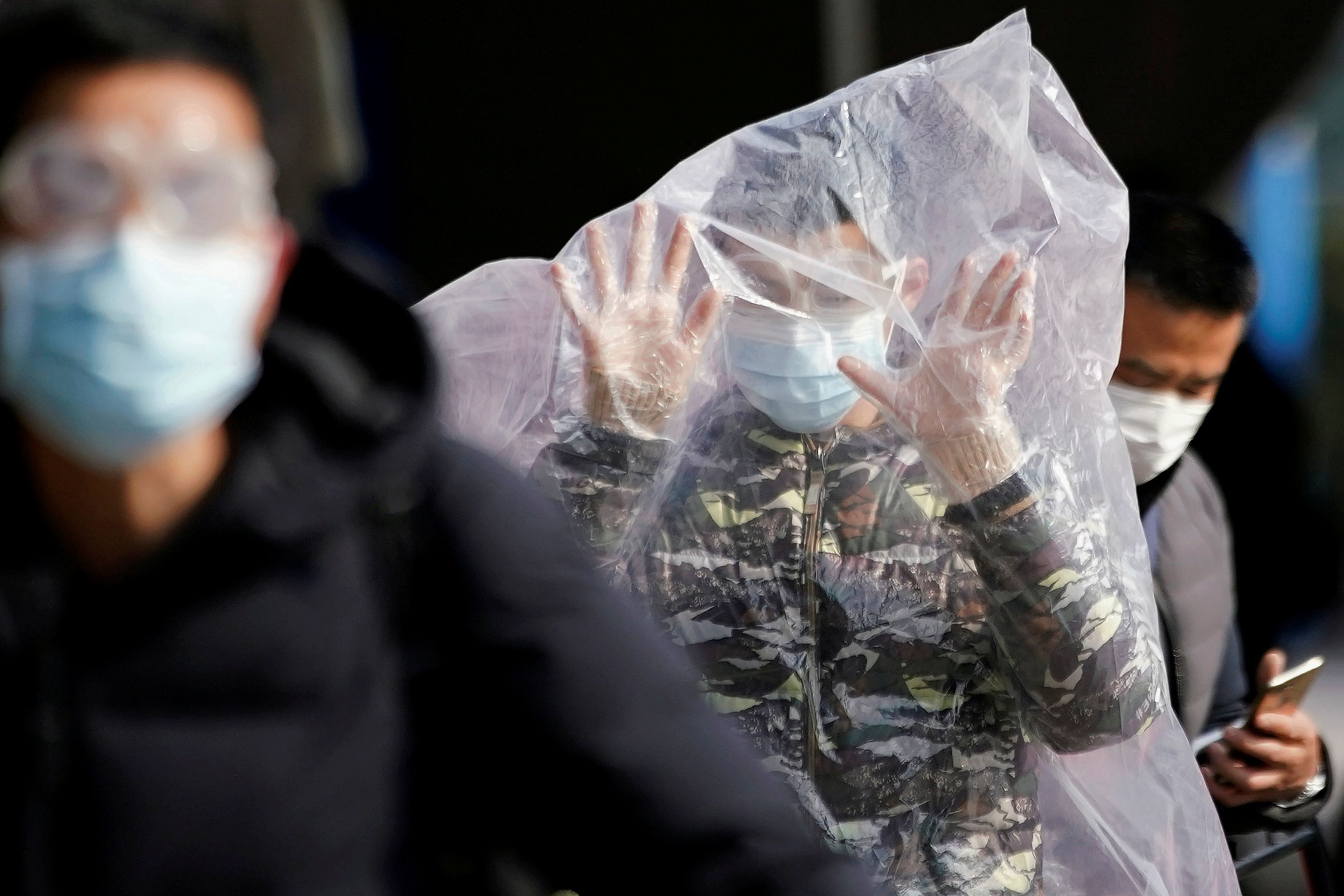 Un hombre camina encerrado en una bolsa de plástico en medio del brote del coronavirus de Wuhan