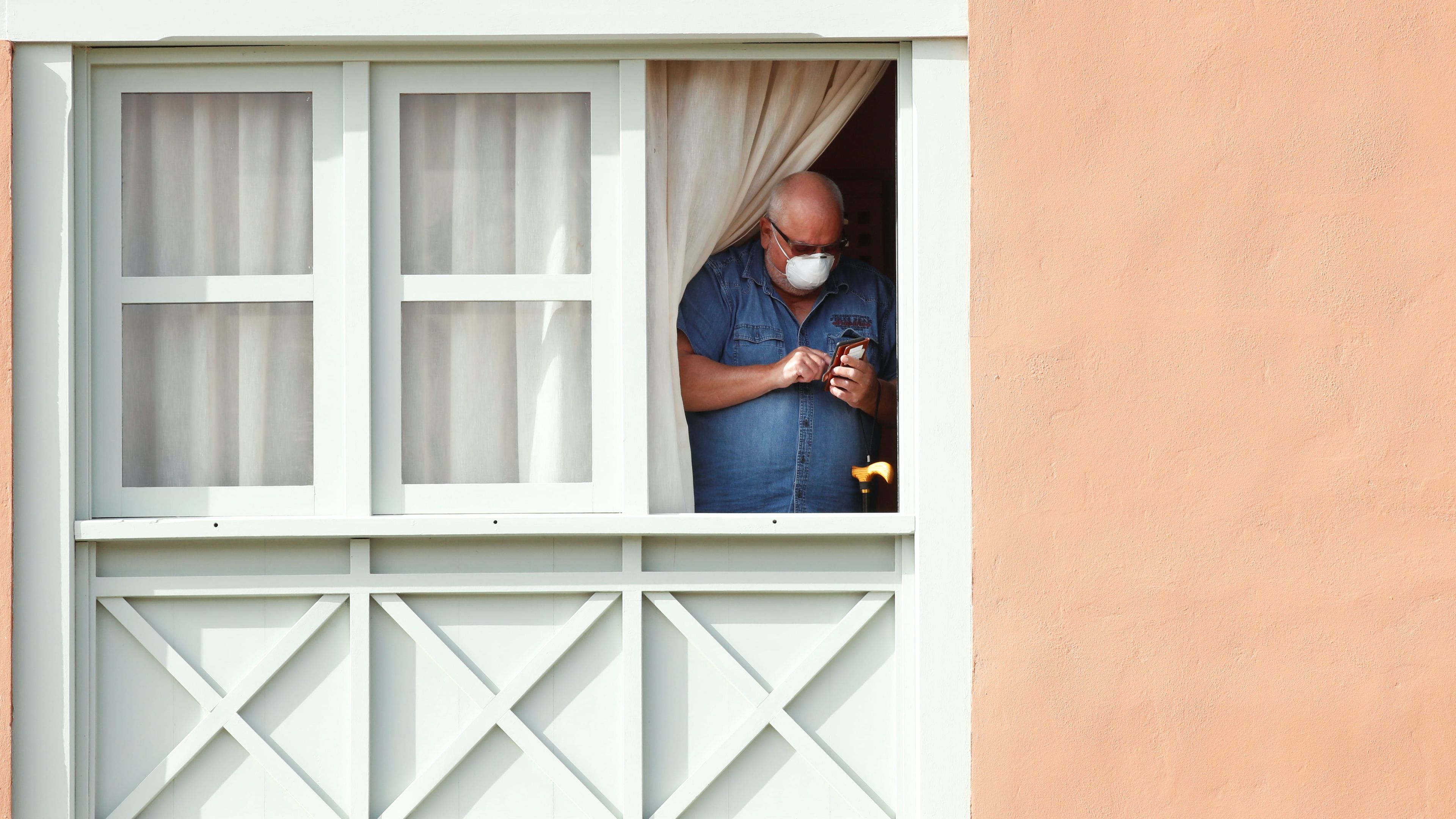 Un hombre con mascarilla se asoma en el hotel de Canarias donde se alojaron enfermos de COVID.