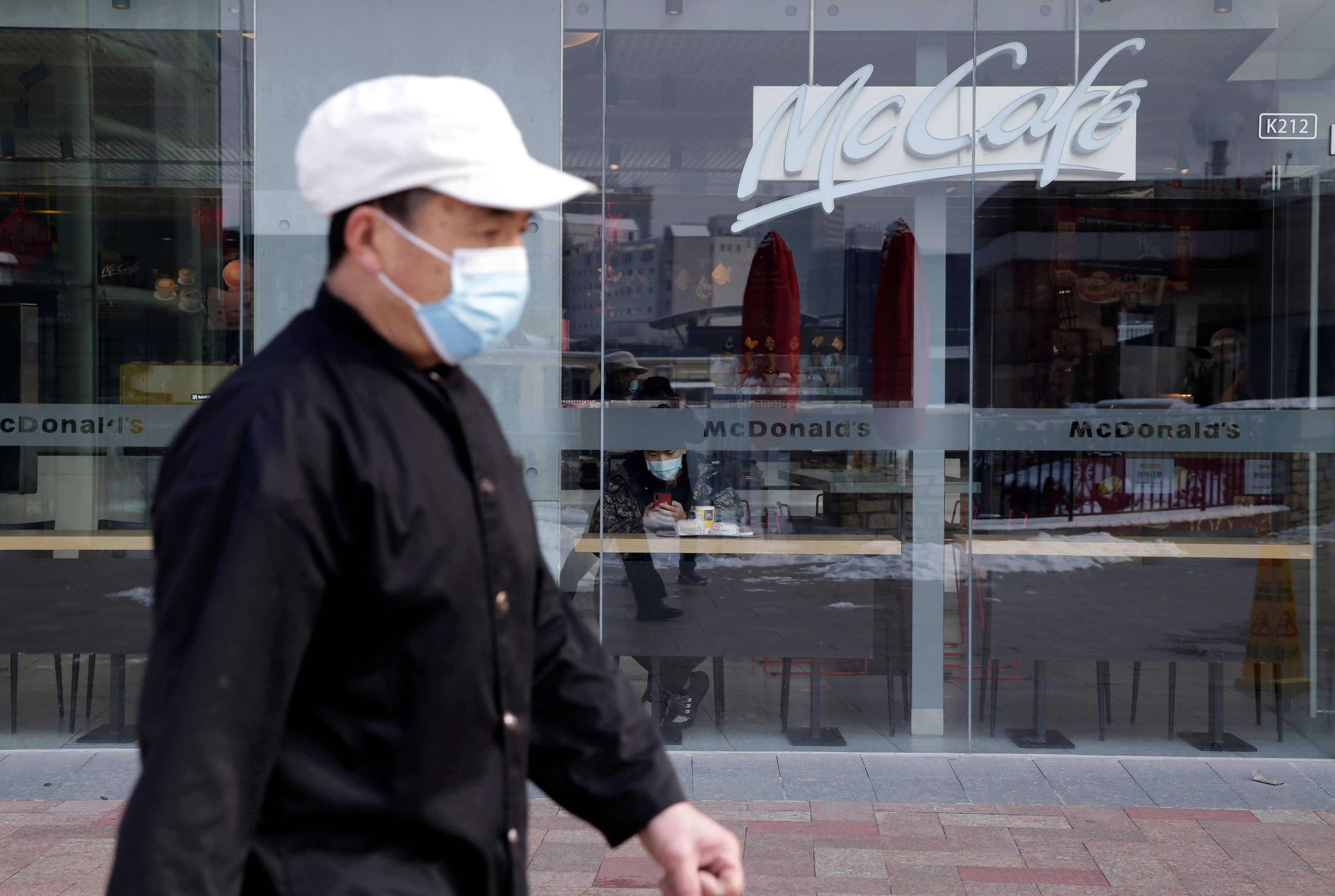 Un hombre con una mascarilla pasa por delante de un establecimiento de Mcdonald's en Pekín