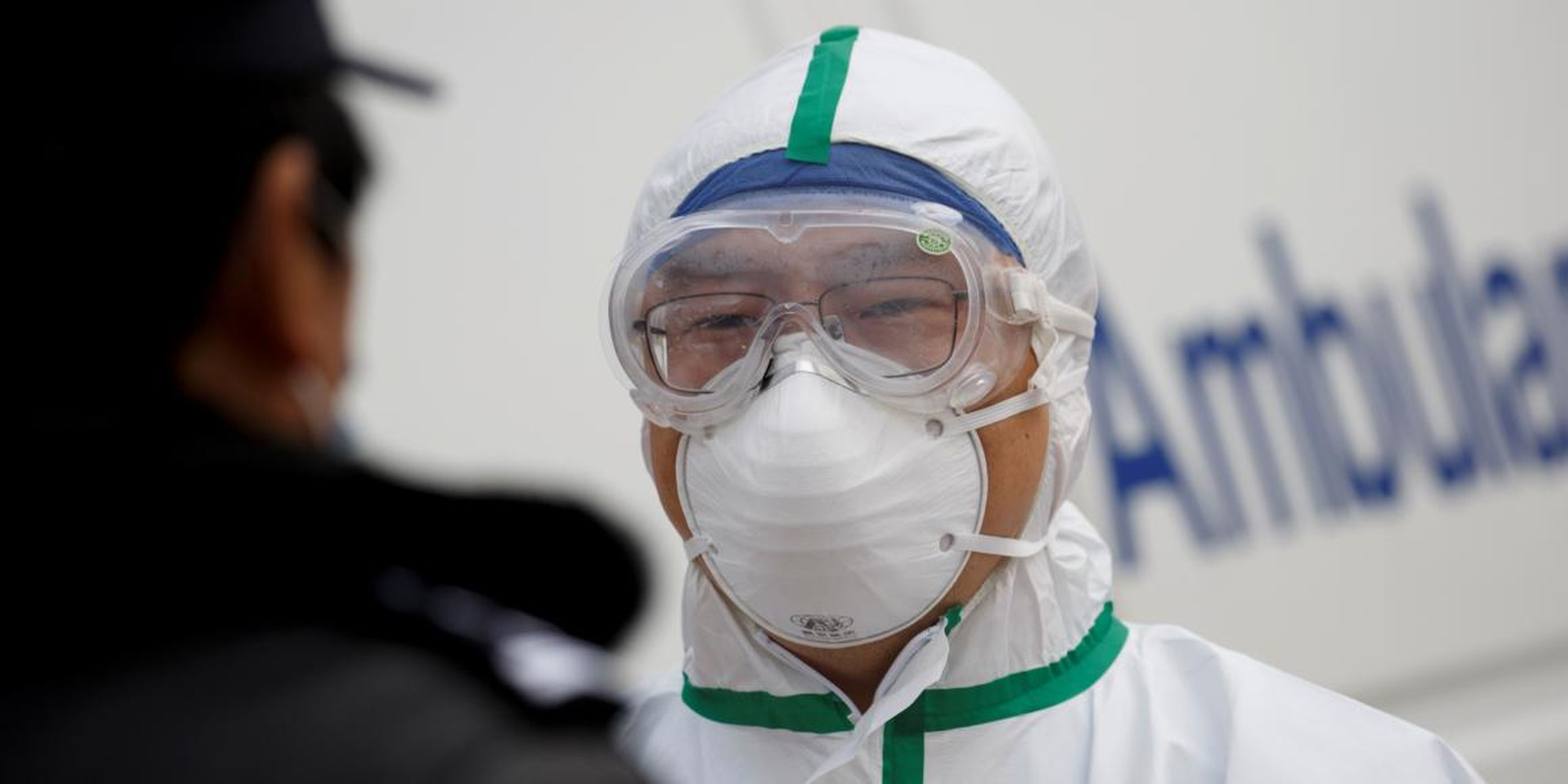 A hospital staff member in protective garments talks to a police officer at a checkpoint to the Hubei province exclusion zone at the Jiujiang Yangtze River Bridge in Jiujiang, Jiangxi province, China, as the country is hit by an outbreak of a new