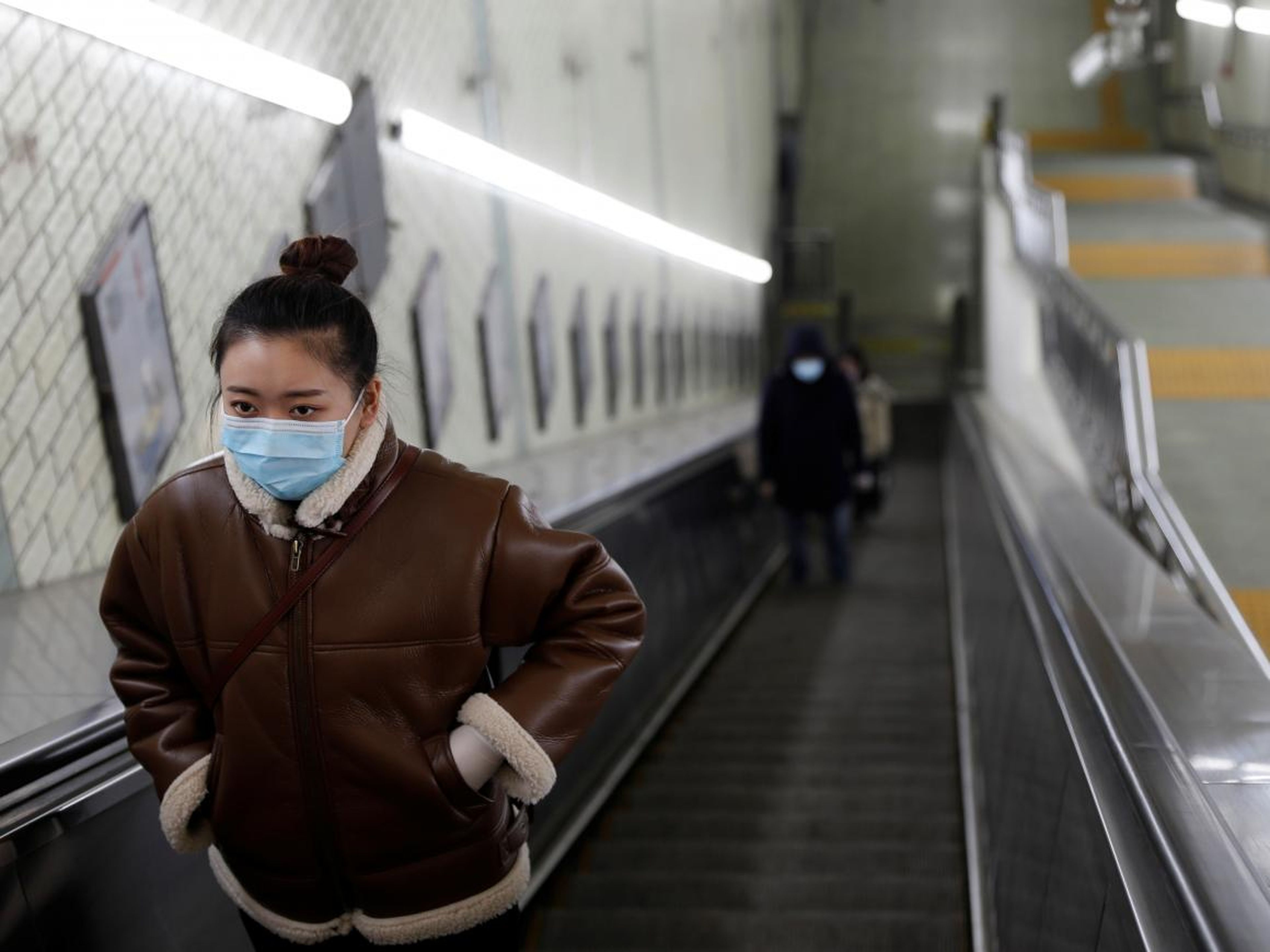 Mujer con una máscara facial en una estación de metro en Pekín.