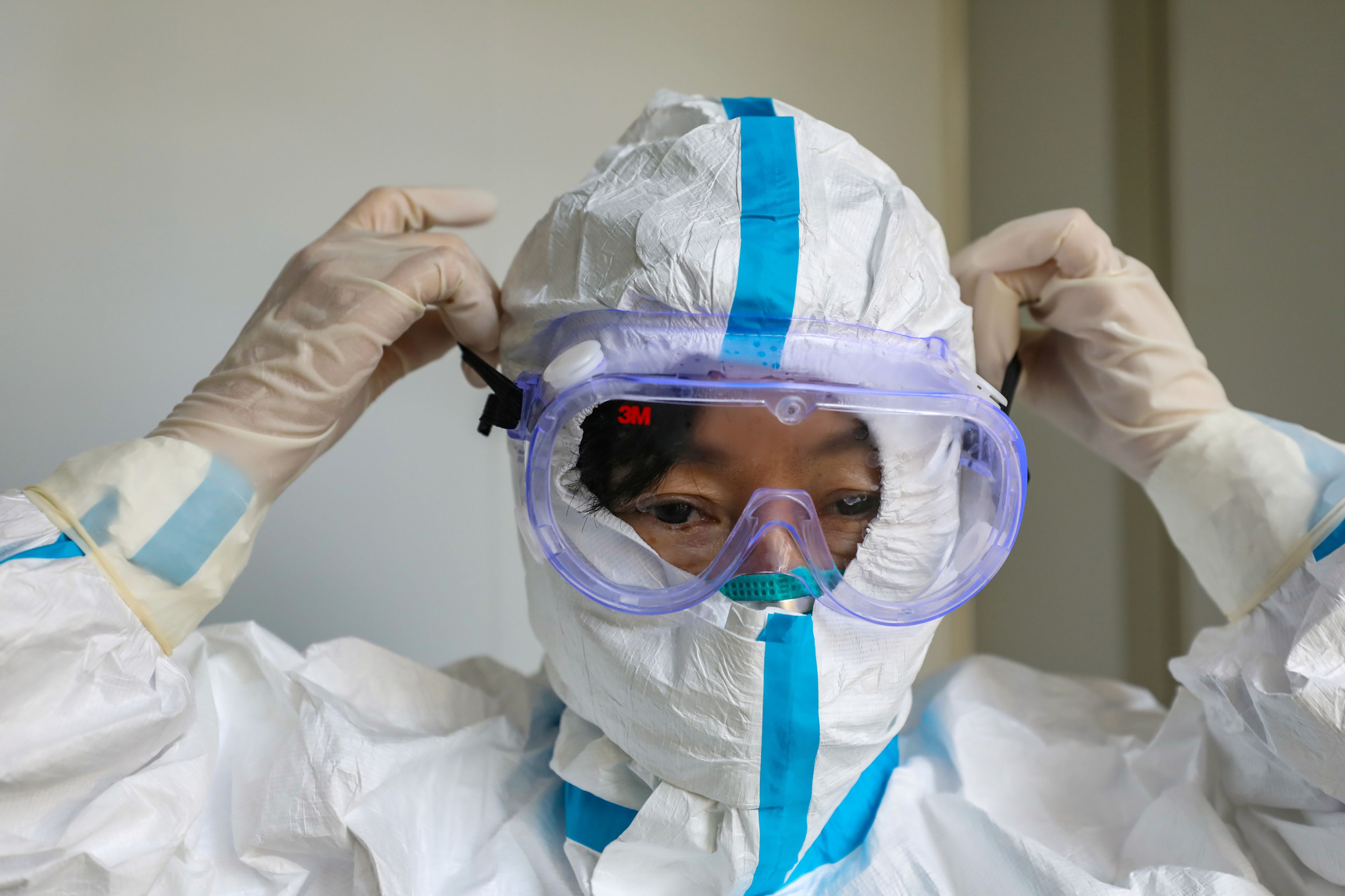 Un médico se pone un traje protector en medio del brote del coronavirus de Wuhan