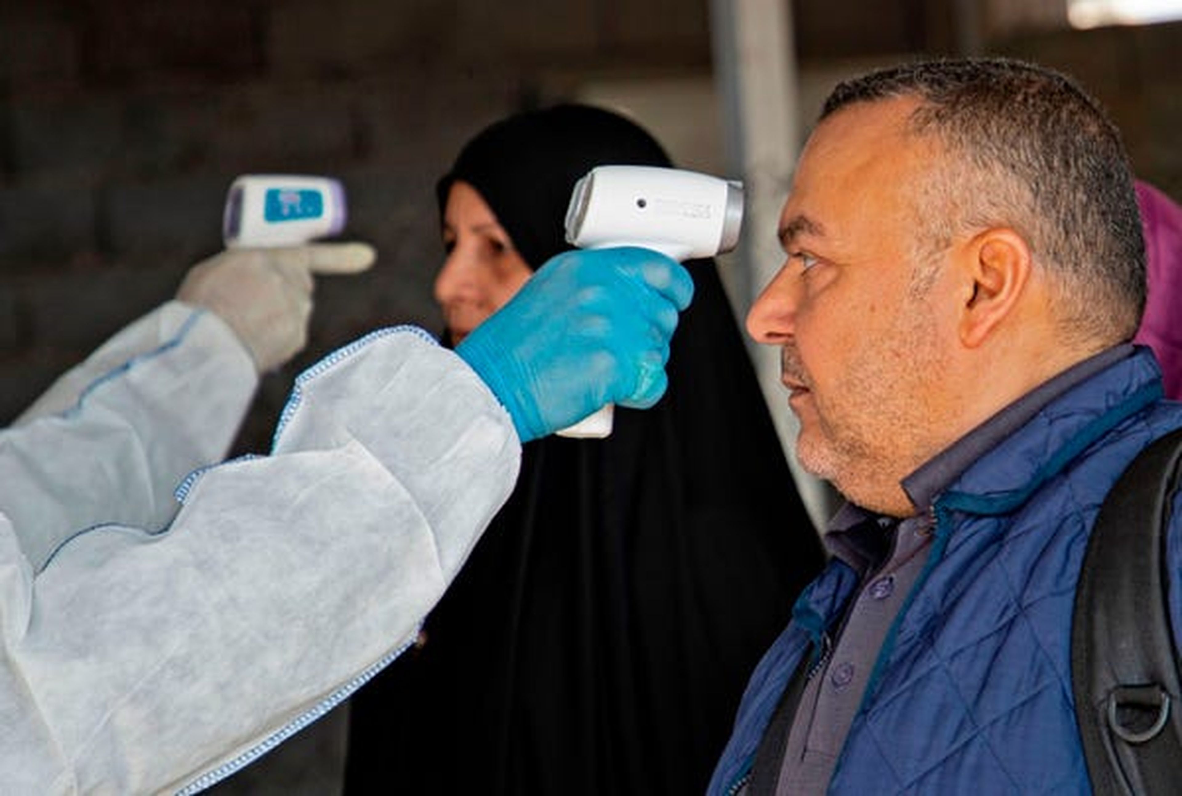 Un miembro del equipo médico le toma la temperatura en la frontera de Shalamjah entre Irán e Iraq el 21 de febrero de 2020.