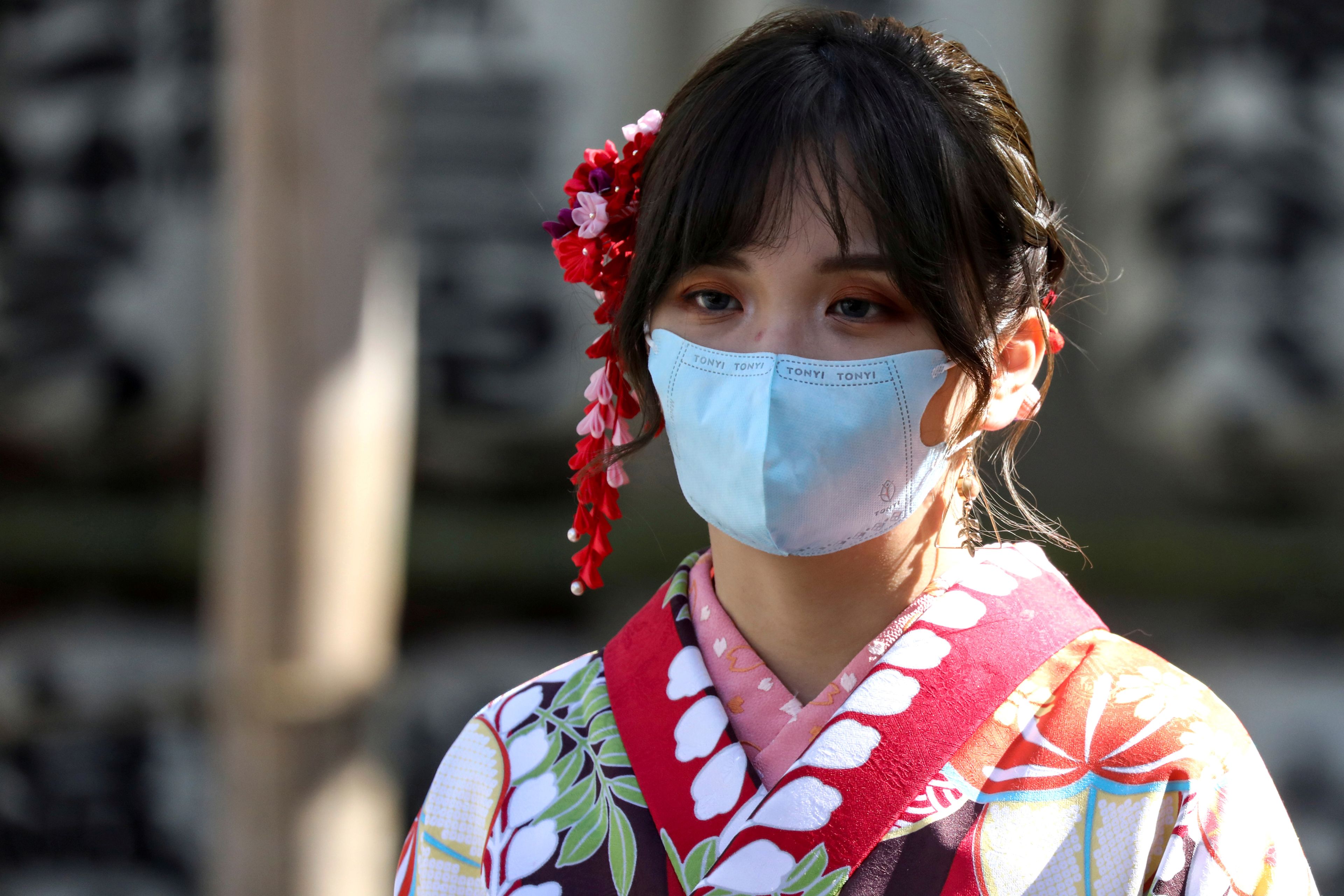 Una mujer pasea con una mascarilla por Tokio para protegerse durante el brote del coronavirus de Wuhan