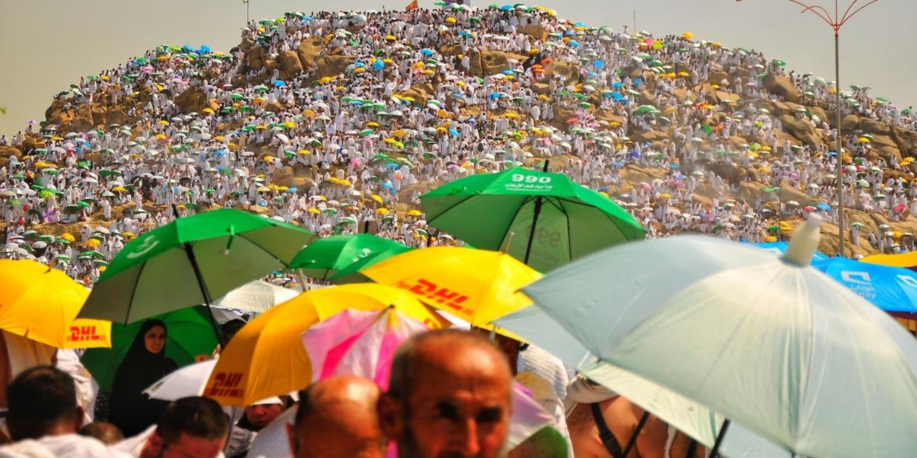 Peregrinos musulmanes llevando paraguas para protegerse del sol.