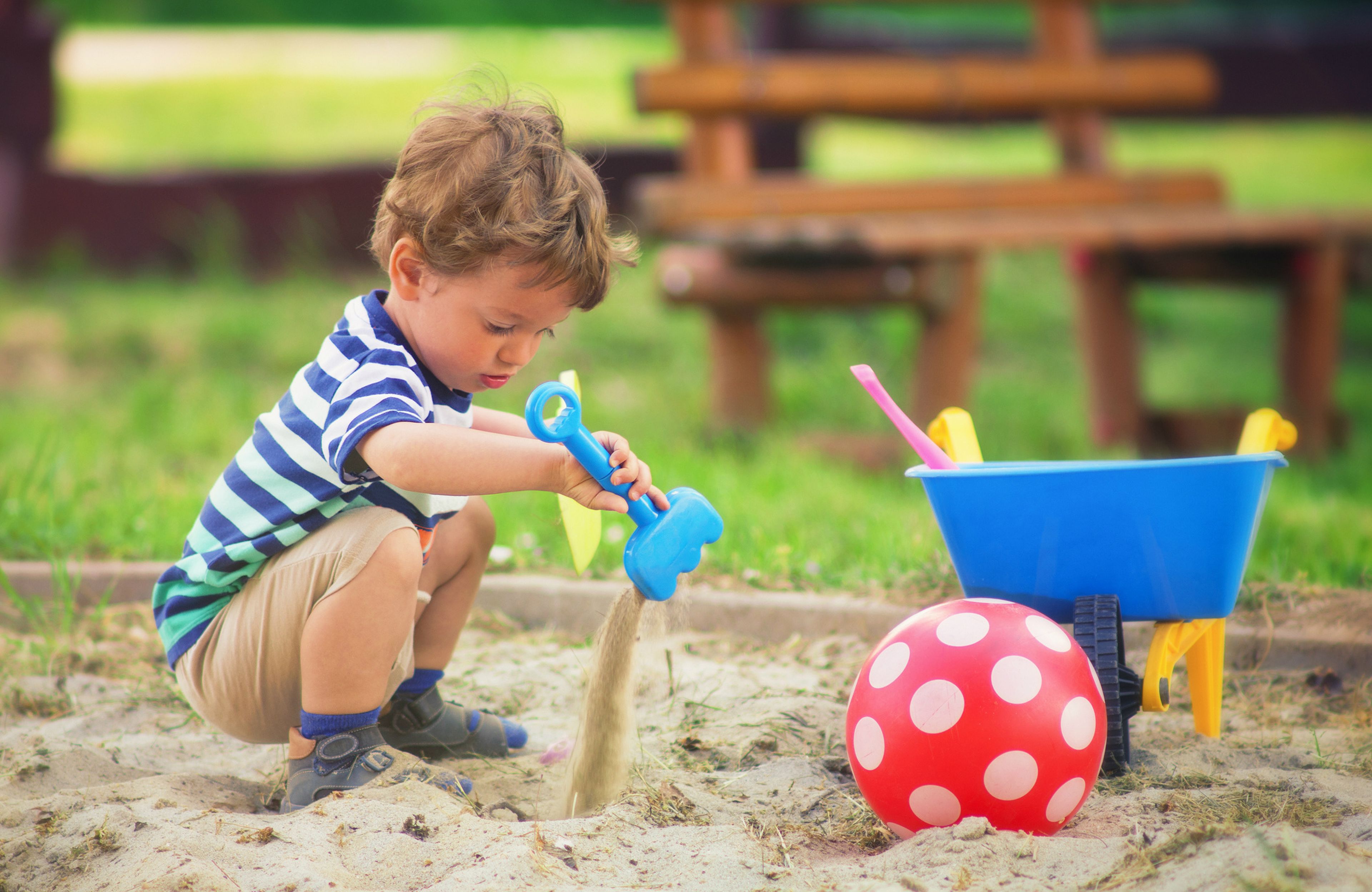 Un niño juega en un cajón de arena, sandbox.