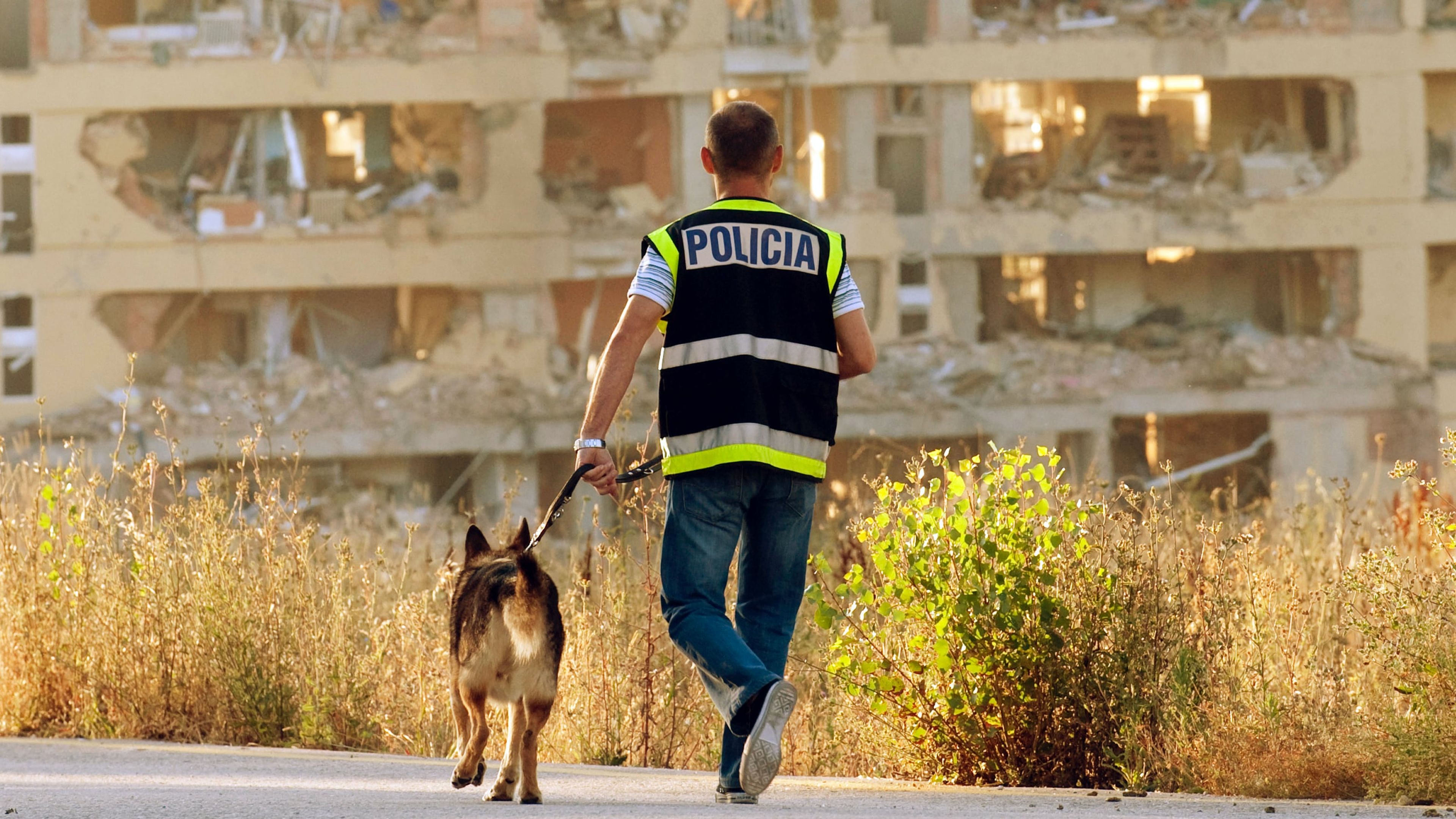 Un perro de la Unidad Canina pasea con un agente de la Policía Nacional.