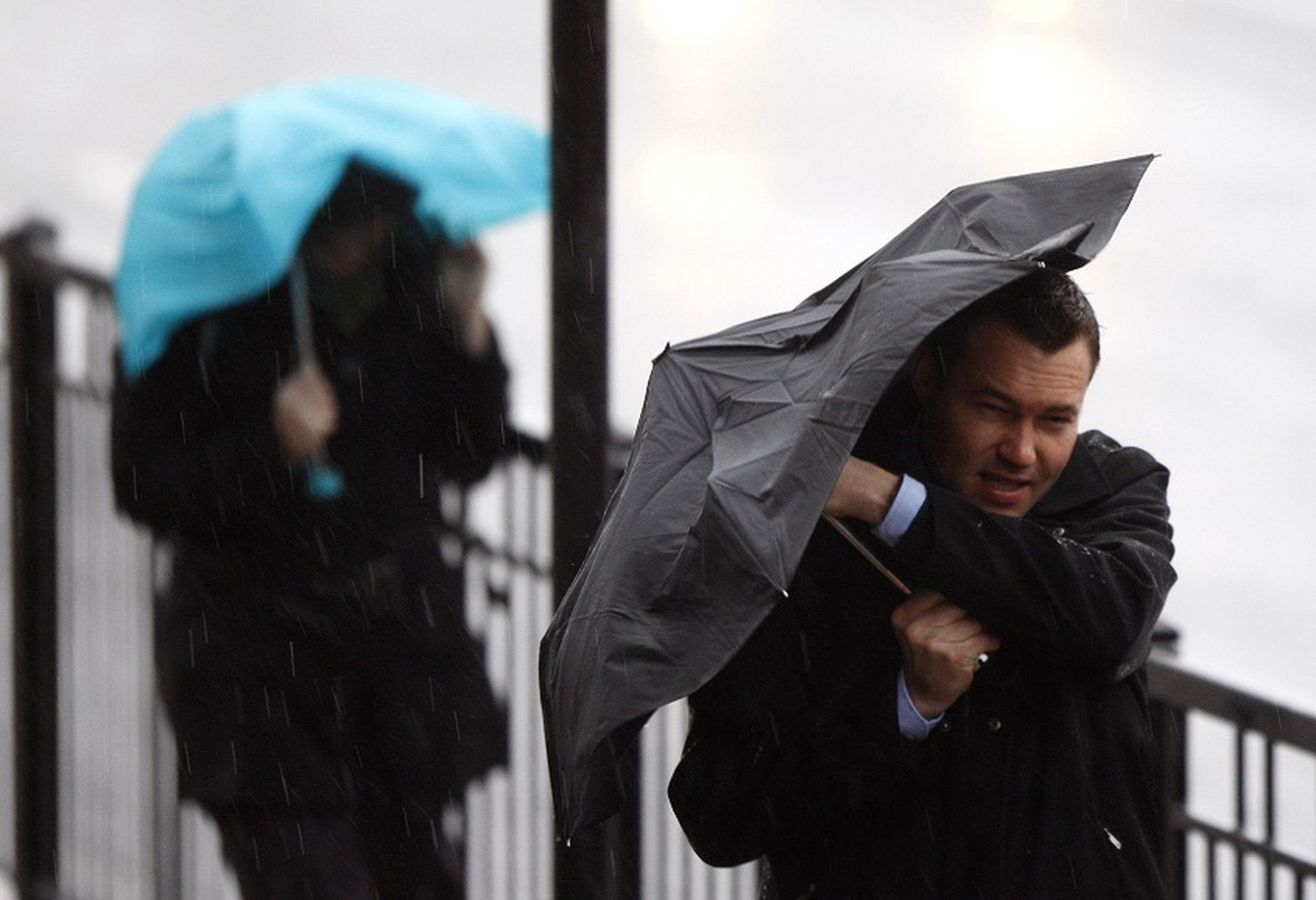 Persona tapándose con un paraguas ante la tormenta