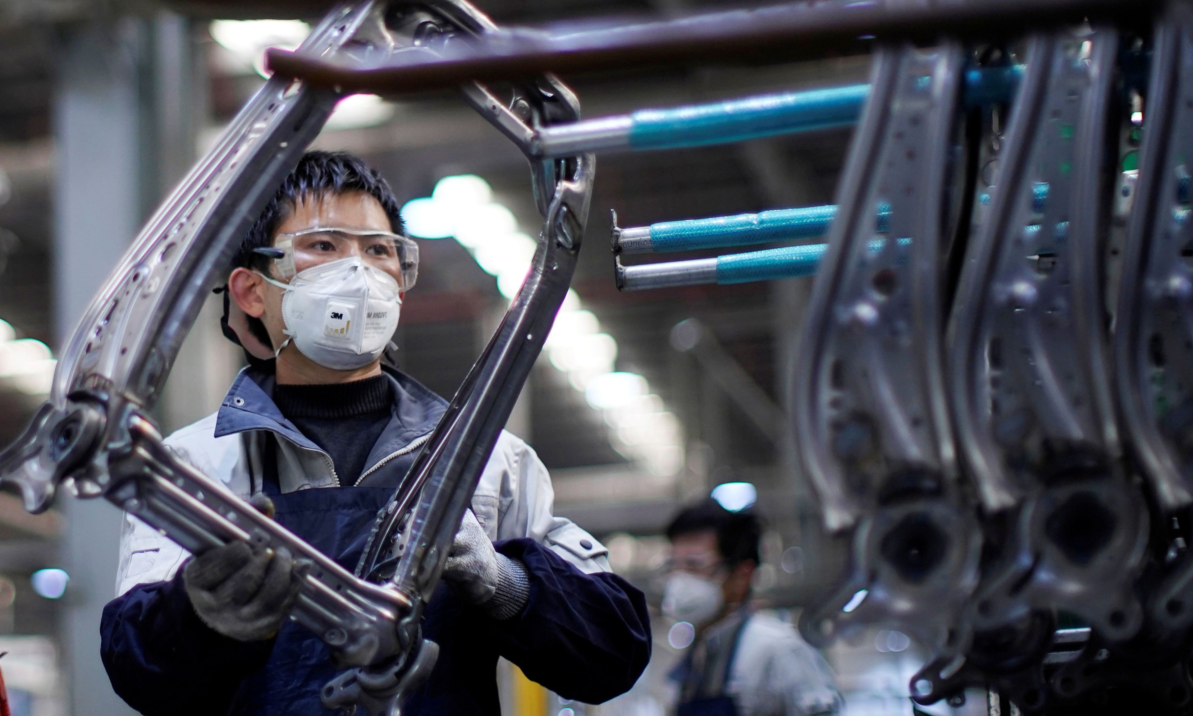 Un trabajador ensambla piezas de asientos de coche en una fábrica en Shanghai
