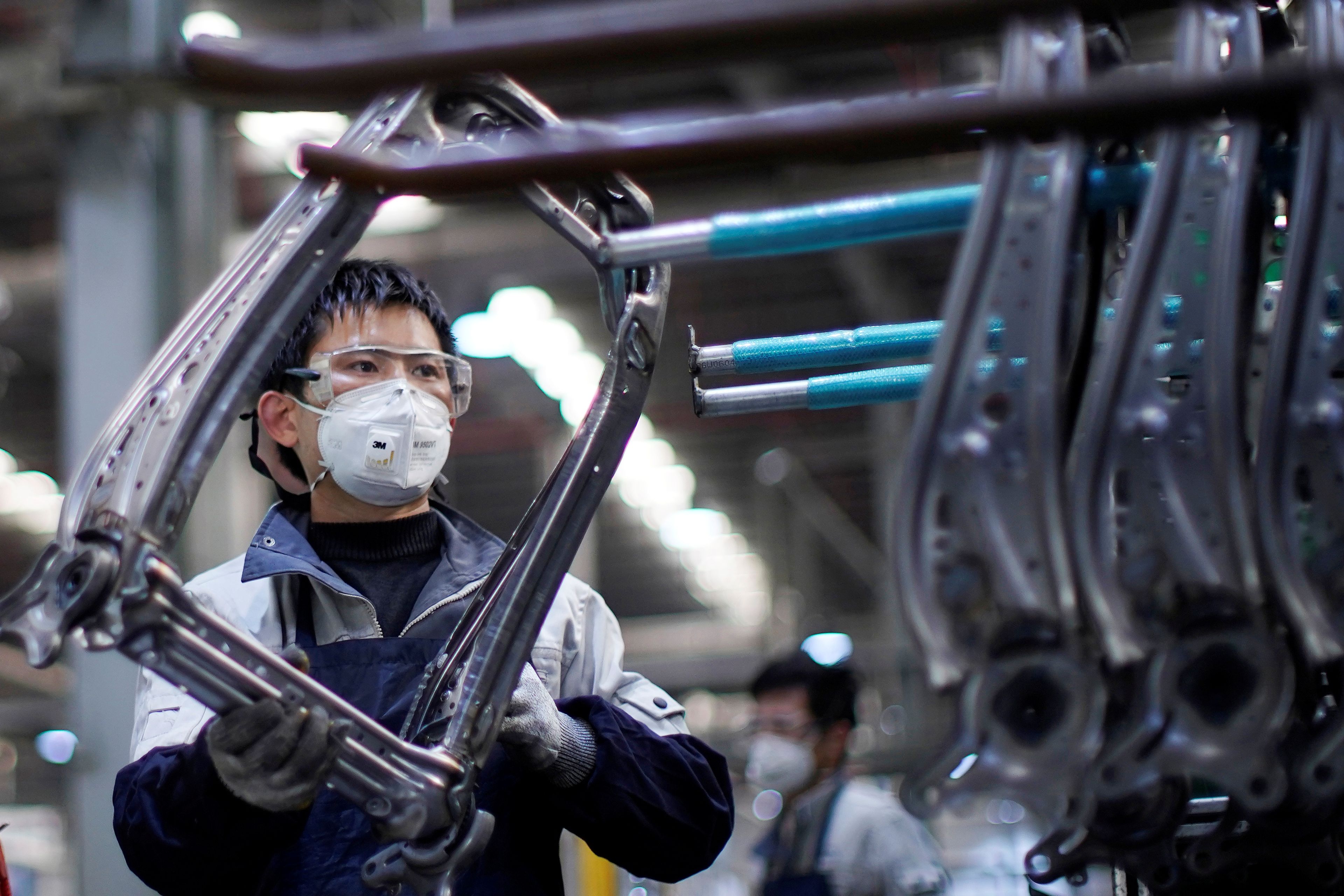 Un trabajador de una fábrica en Shanghái con una mascarilla por miedo a los contagios por el coronavirus