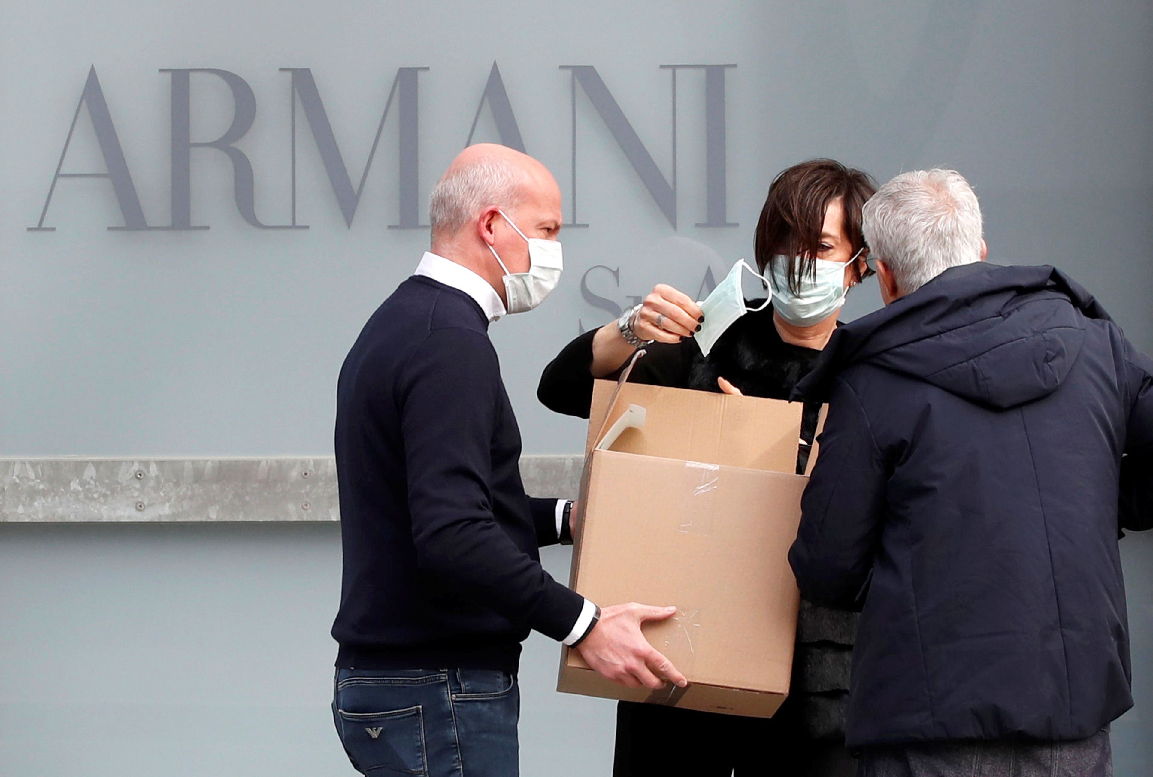 Trabajadores reparten mascarillas a las puertas del teatro donde Giorgio Armani tenía previsto realizar su desfile de la semana de la moda de Milán.