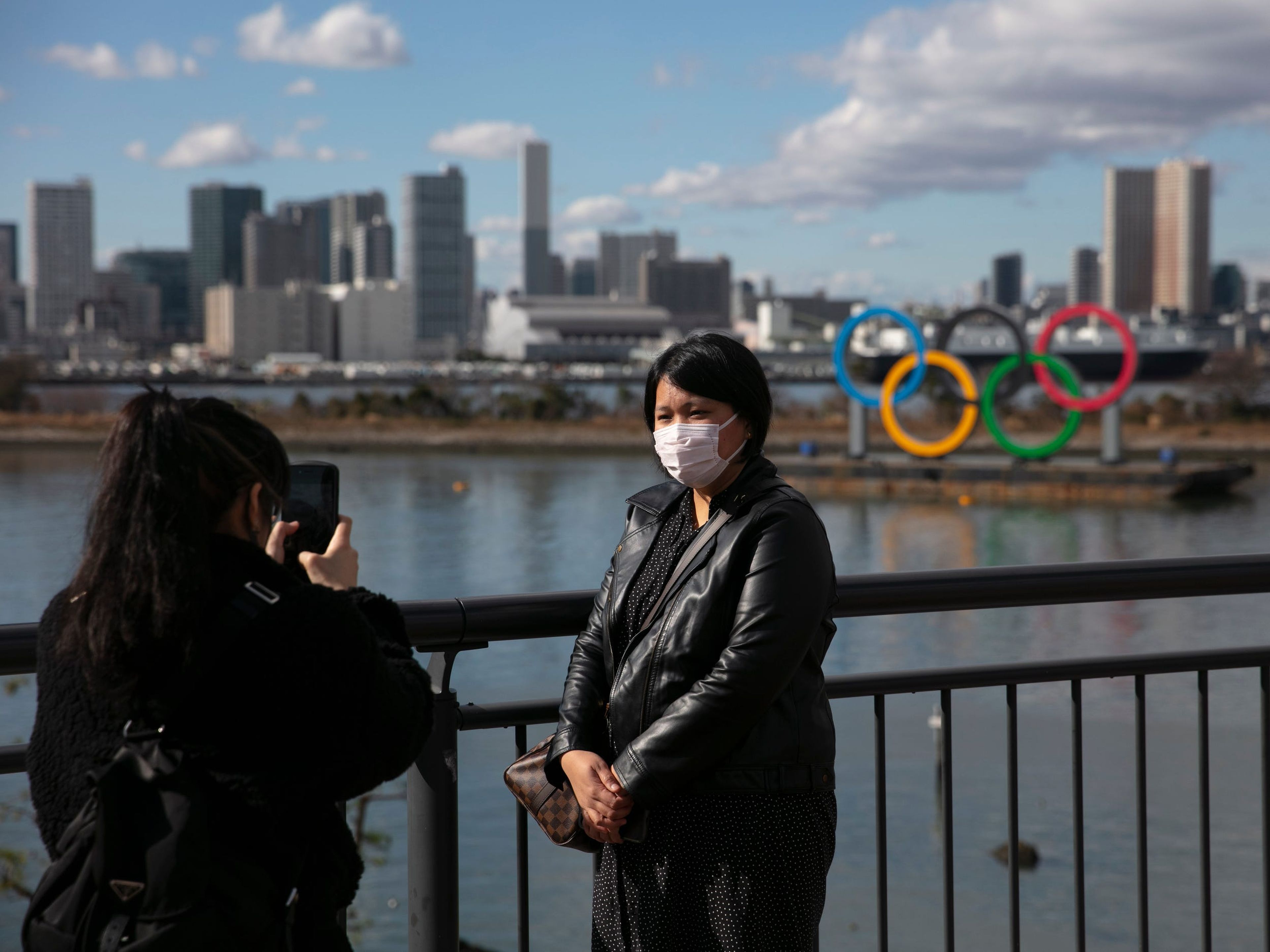 Una turista con máscara se hace una foto frente a los anillos olímpicos en el distrito de Odaiba de Tokio.