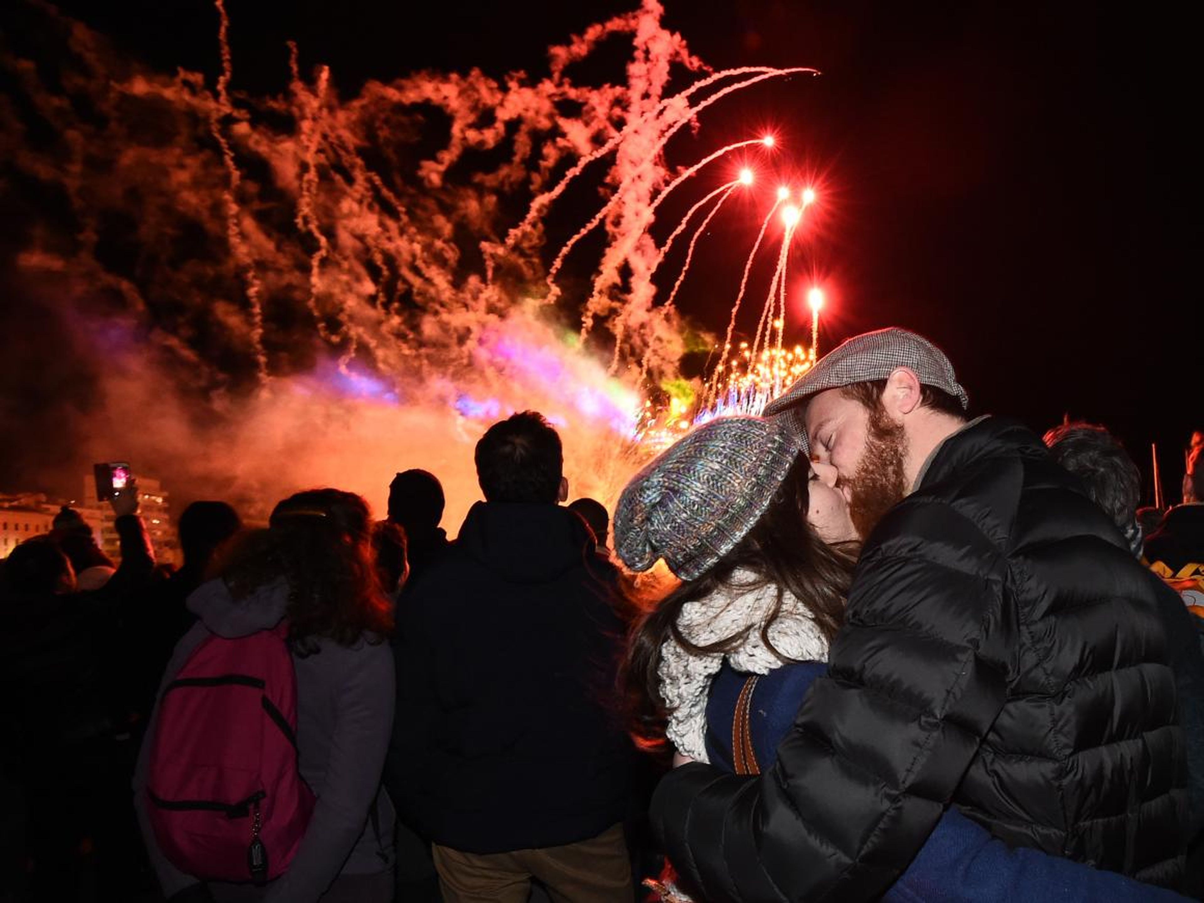 Una pareja se besa mientras asiste a un espectáculo de fuegos artificiales.