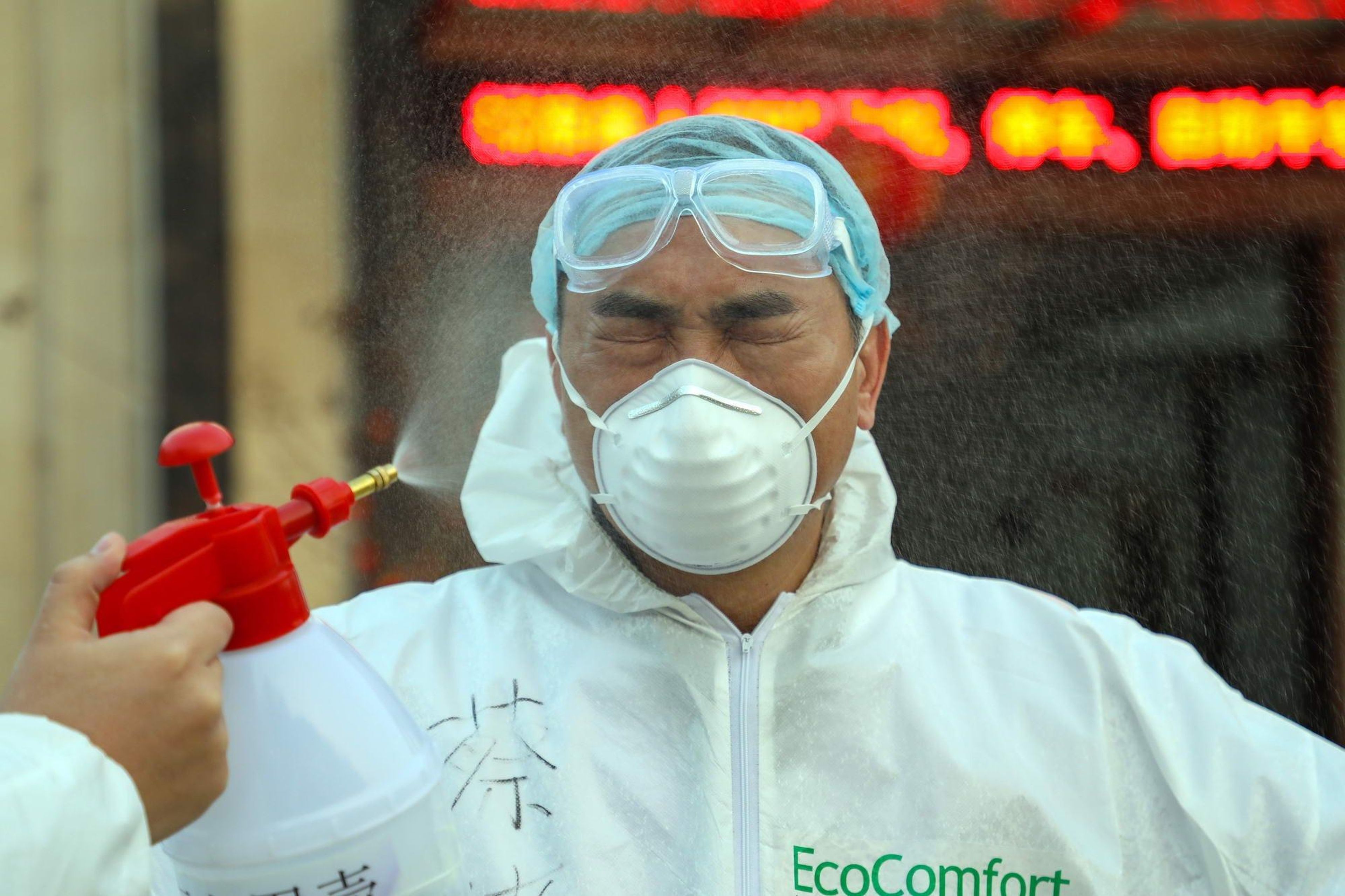 A worker disinfects a doctor with alcohol spray as he leaves a hotel accommodating isolated people in Wuhan, China.