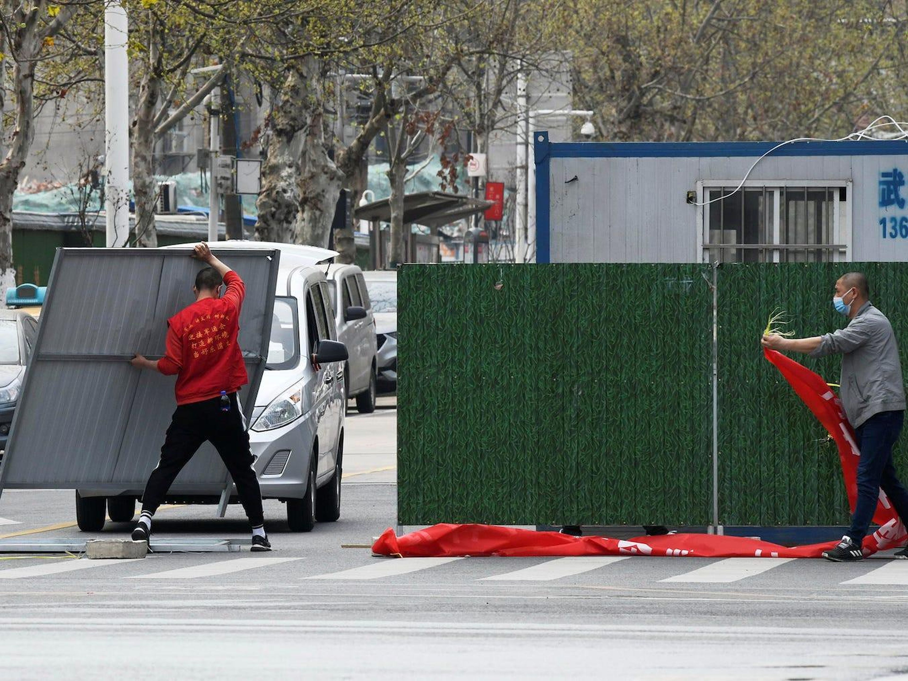 Trabajadores con mascarillas eliminan las barreras en una calle de Wuhan el 21 de marzo de 2020.