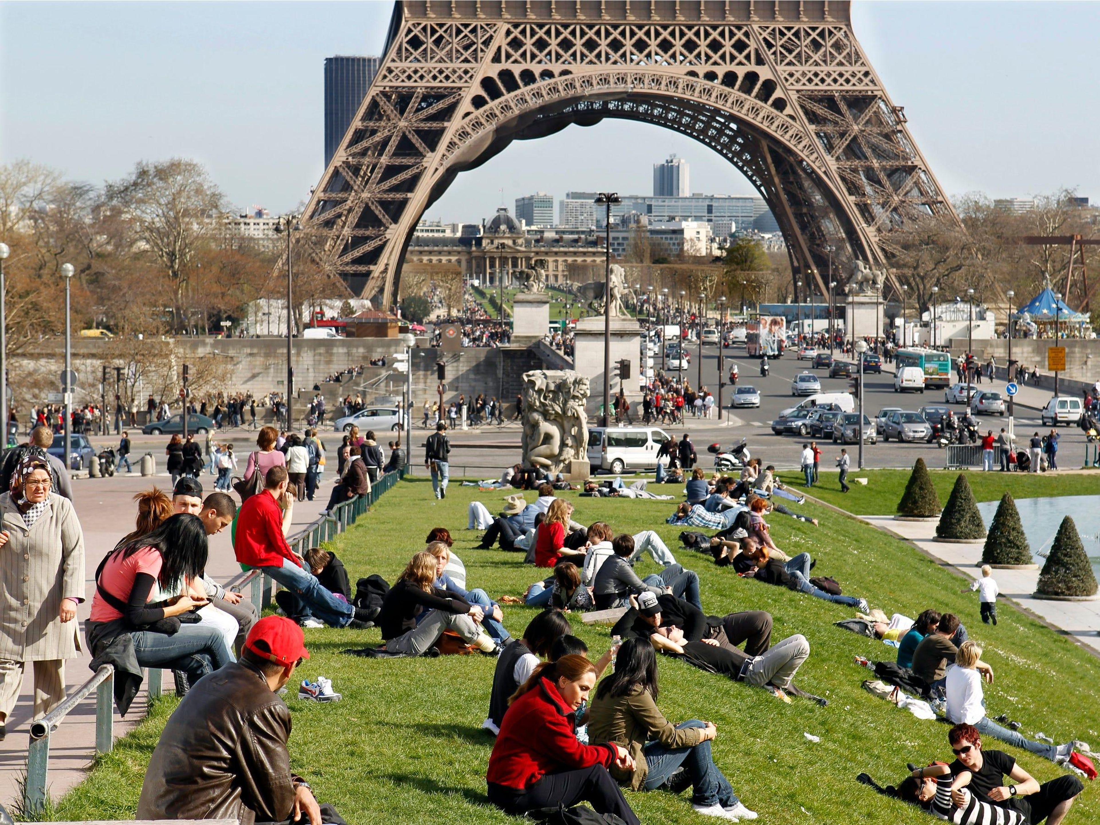 Parisinos y turistas se relajan en la hierba cerca de la Torre Eiffel.