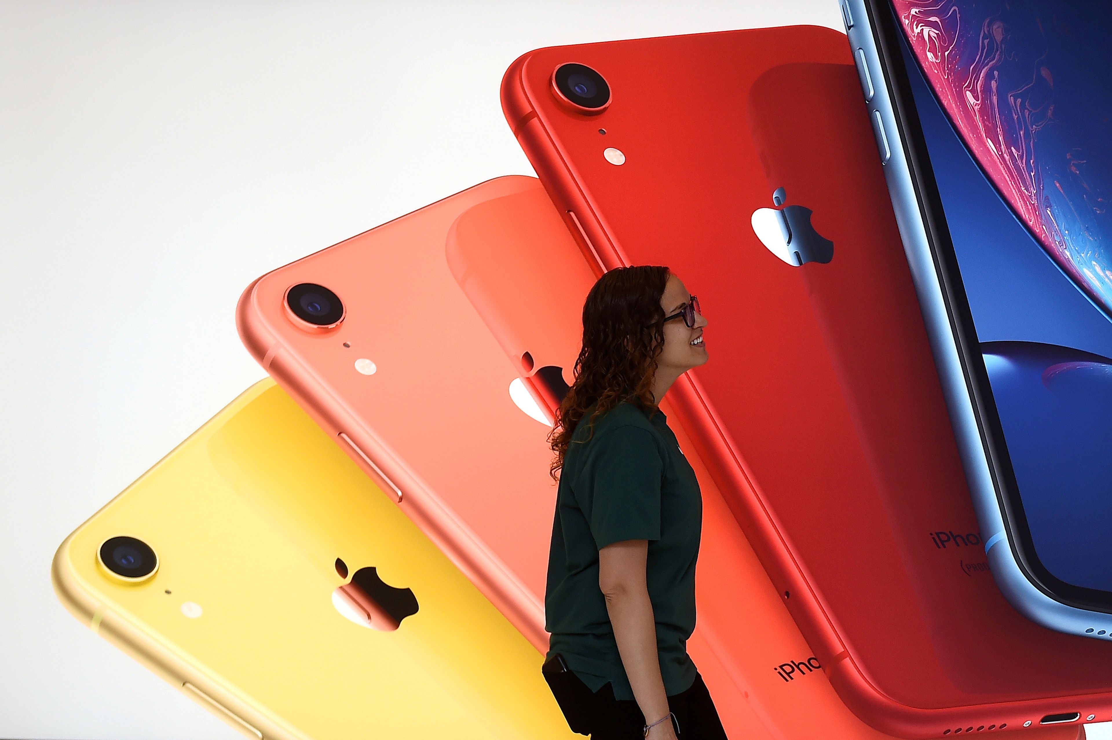 Una empleada de una Apple Store pasa por delante de un mural con los iPhone
