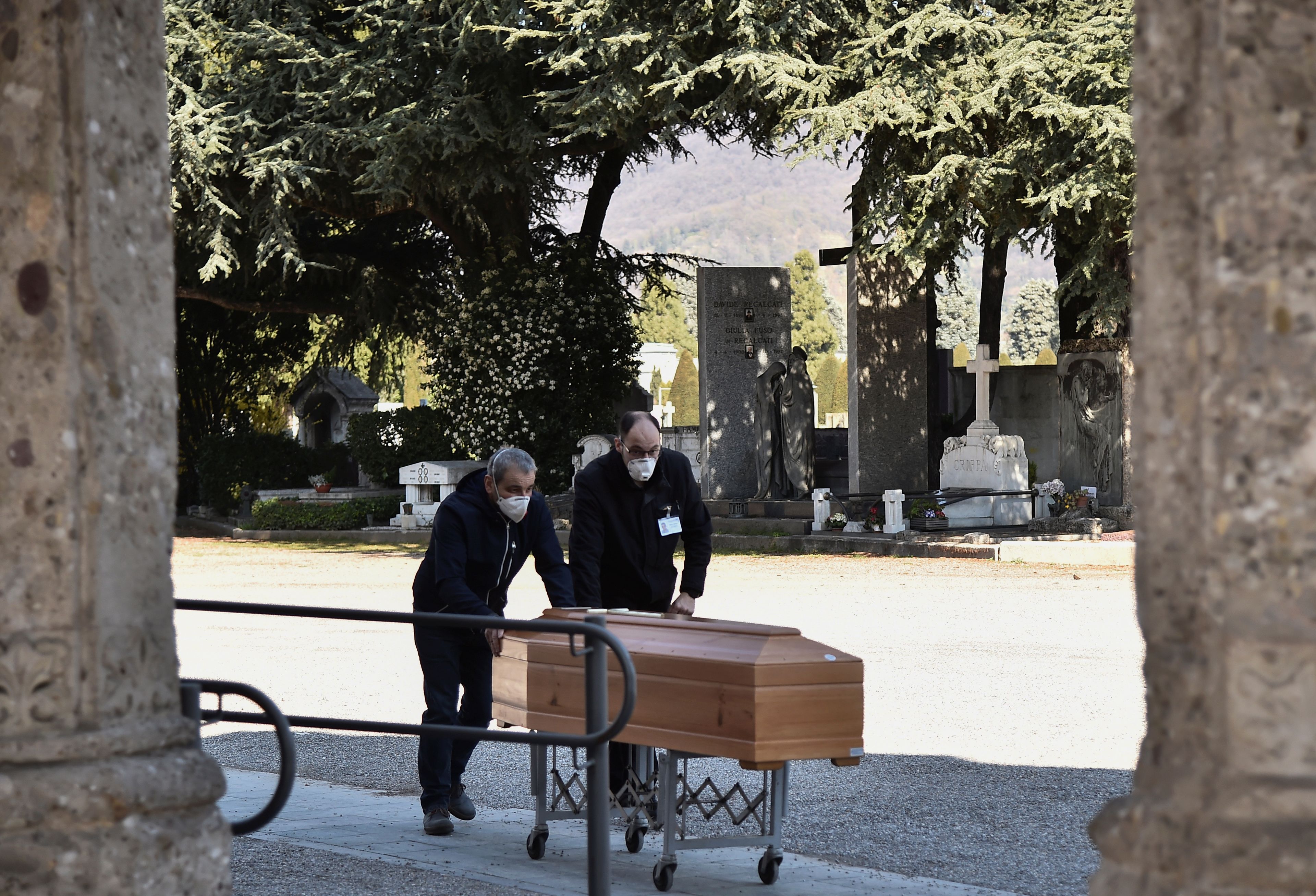 Dos personas transportan un ataúd dentro de un cementerio en Bérgamo, Italia, el 16 de marzo de 2020.