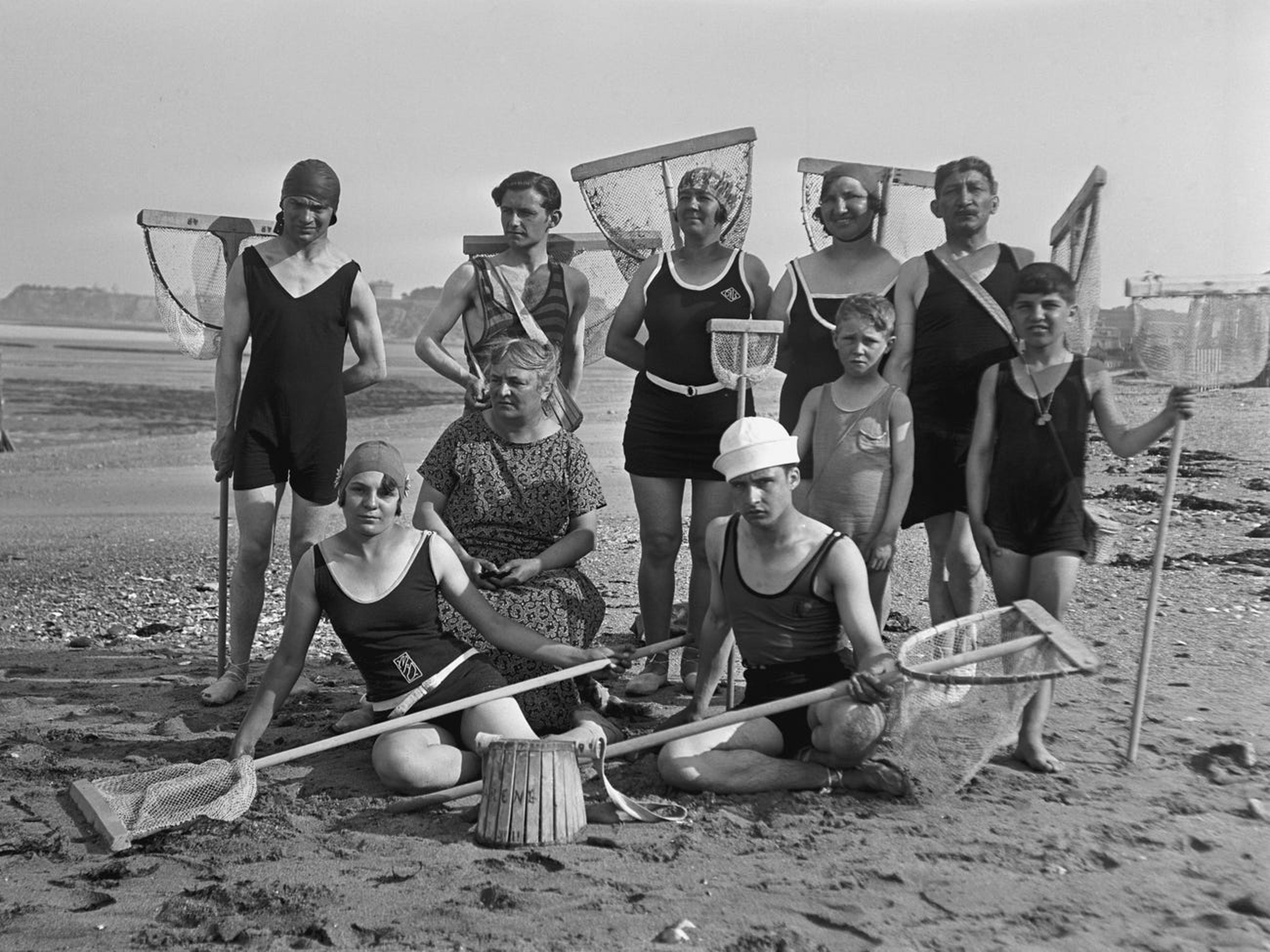 Una gran familia de hombres, mujeres y niños, todos con redes de camarones en una playa de Alemania, alrededor de 1920.