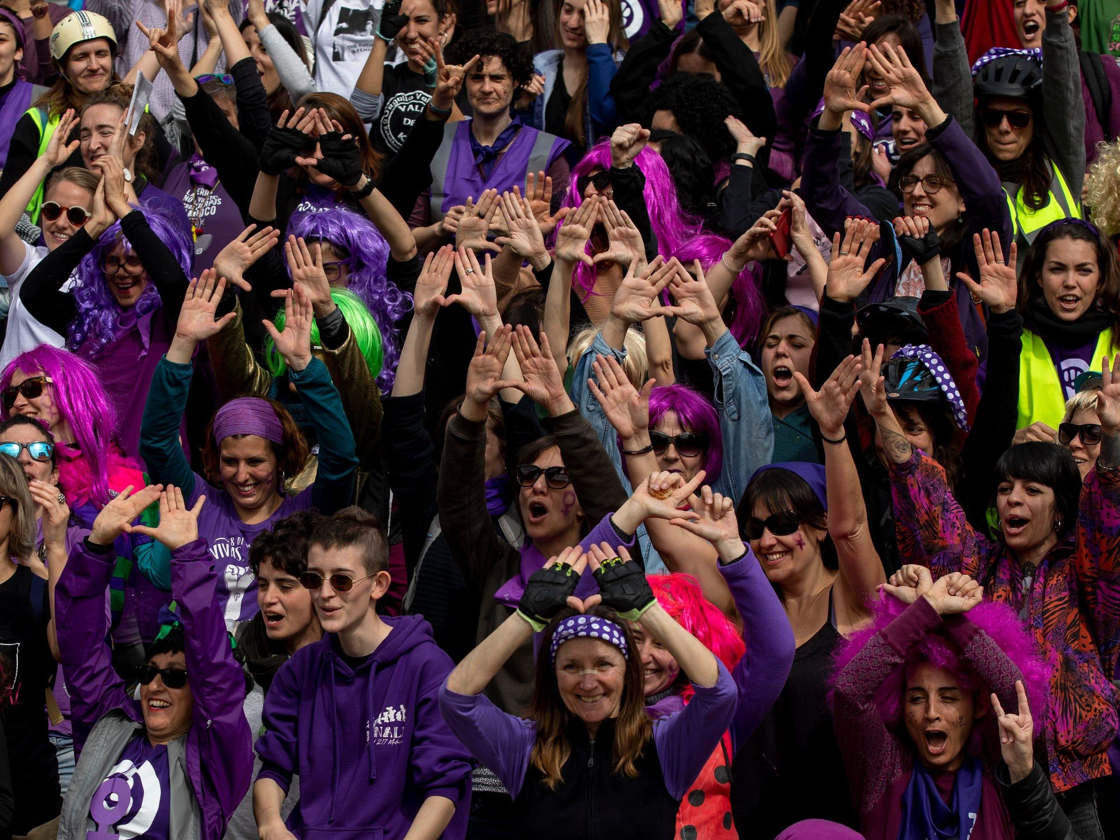 Groups of people display feminist hand symbols at a parade in Madrid, Spain.