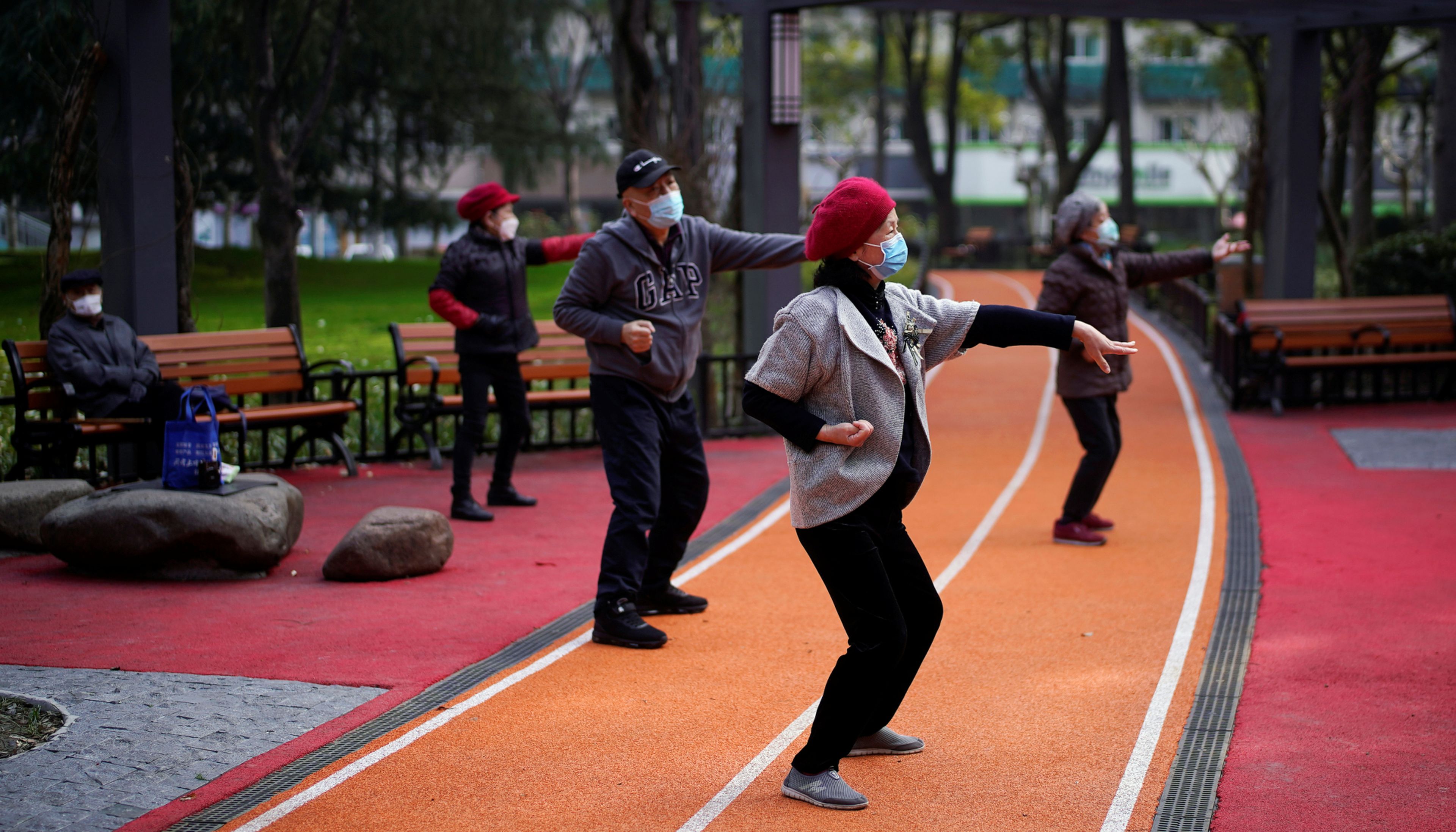 Un grupo de ancianos con mascarillas hacen tai chi en un parque de Pekín