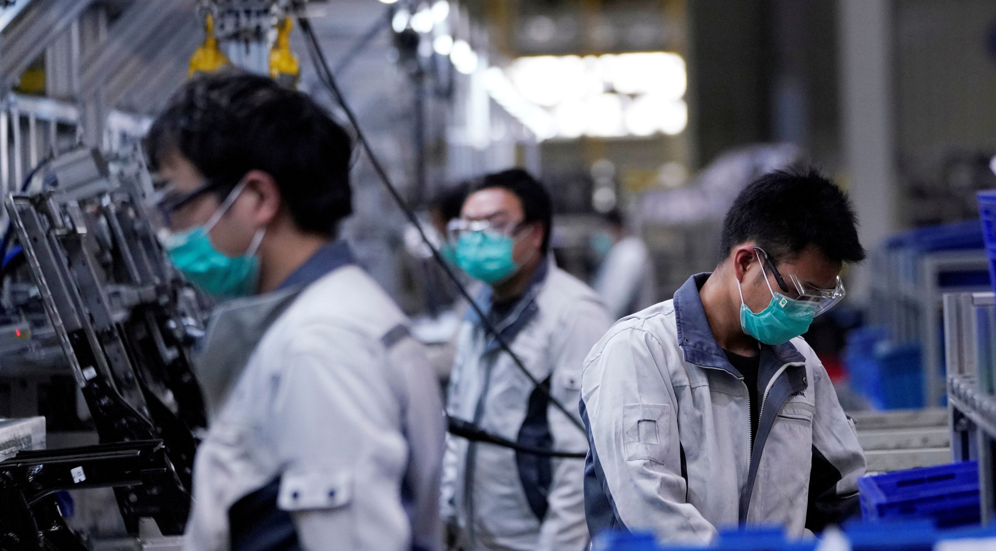 Un grupo de trabajadores de una planta automovilística en Shanghai (China), con mascarillas y gafas protectoras