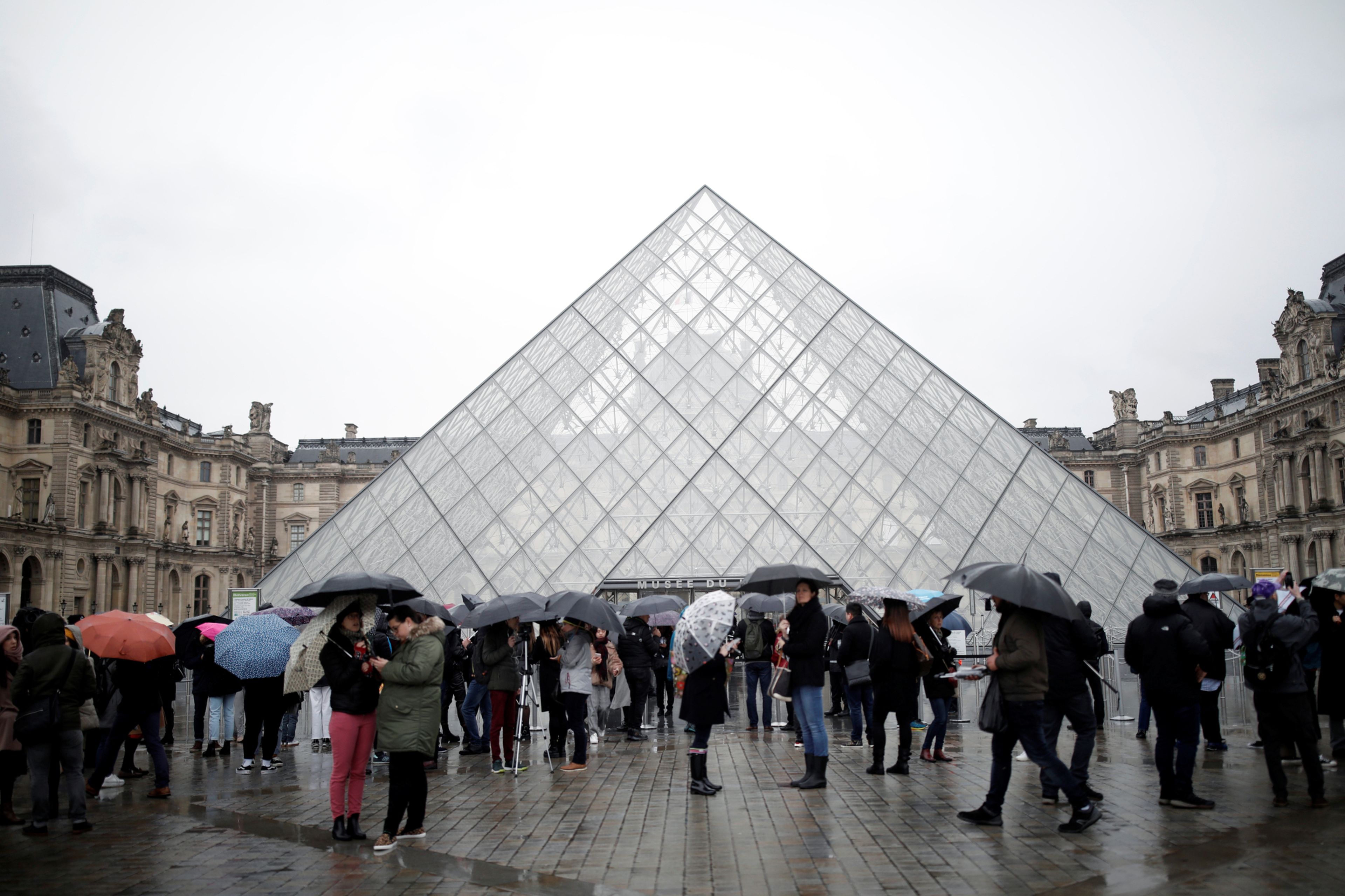 Grupos de turistas se agolpan en la entrada del Museo del Louvre de París (Francia)