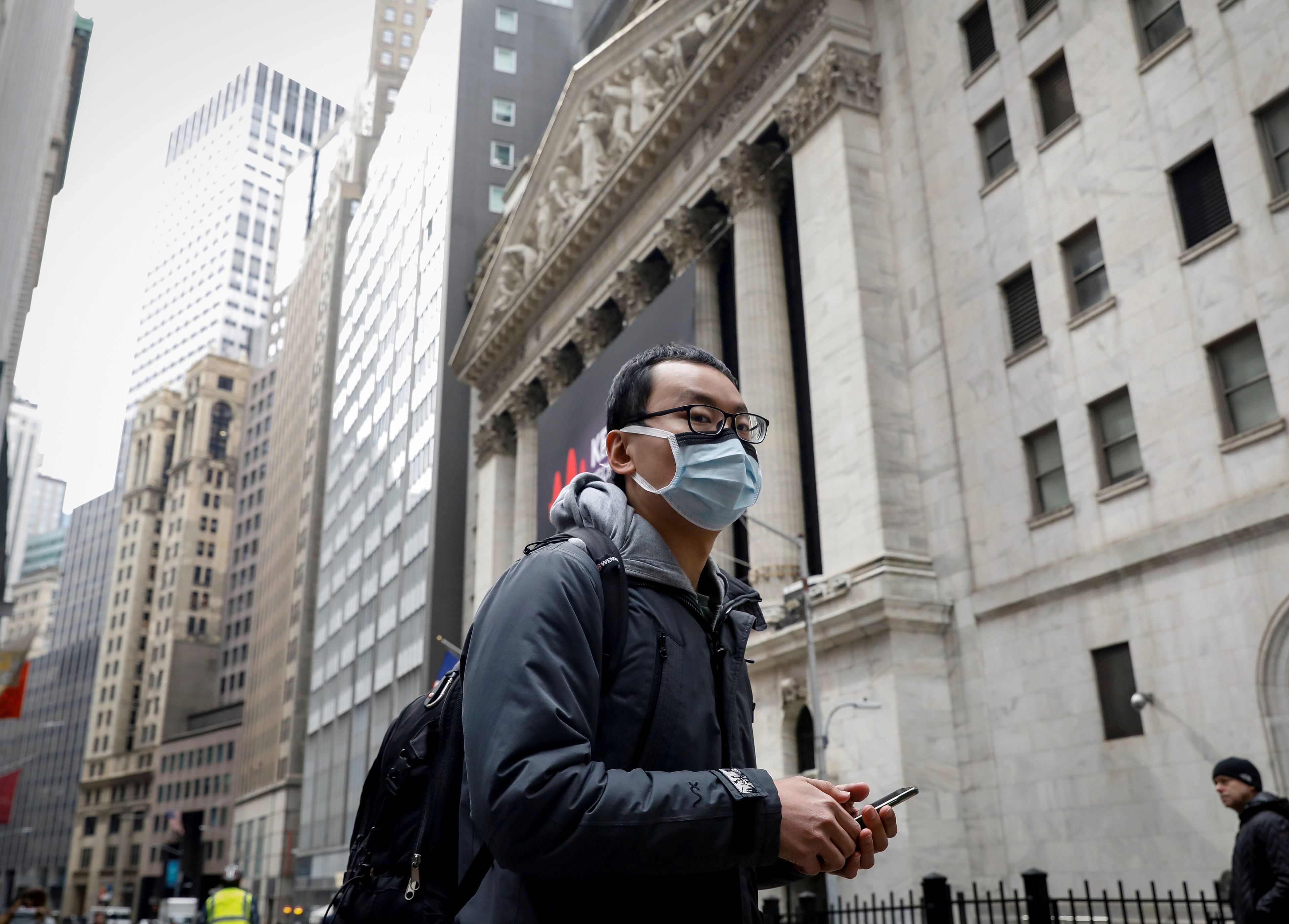 Hombre pase por Wall Street con una mascarilla.