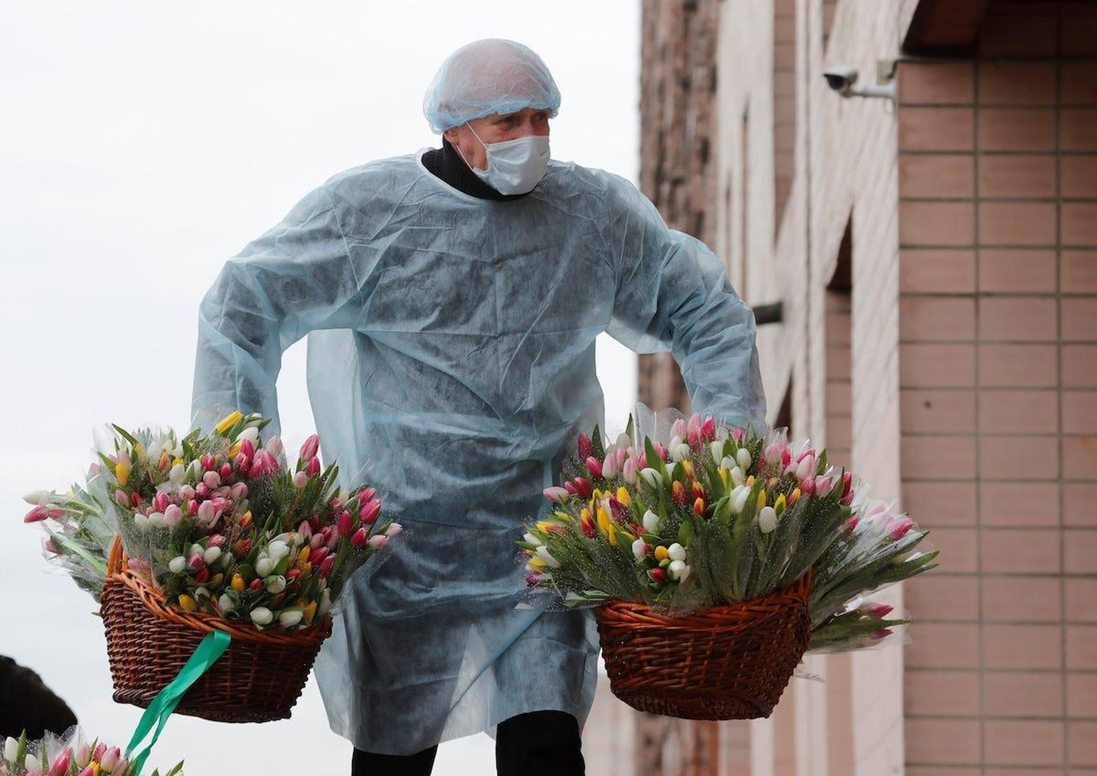 A man wearing a protective suit carries flowers for female students of the Mechnikov North-Western State Medical University in Saint Petersburg, Russia. The students are under quarantine at the dormitory as part of precautions