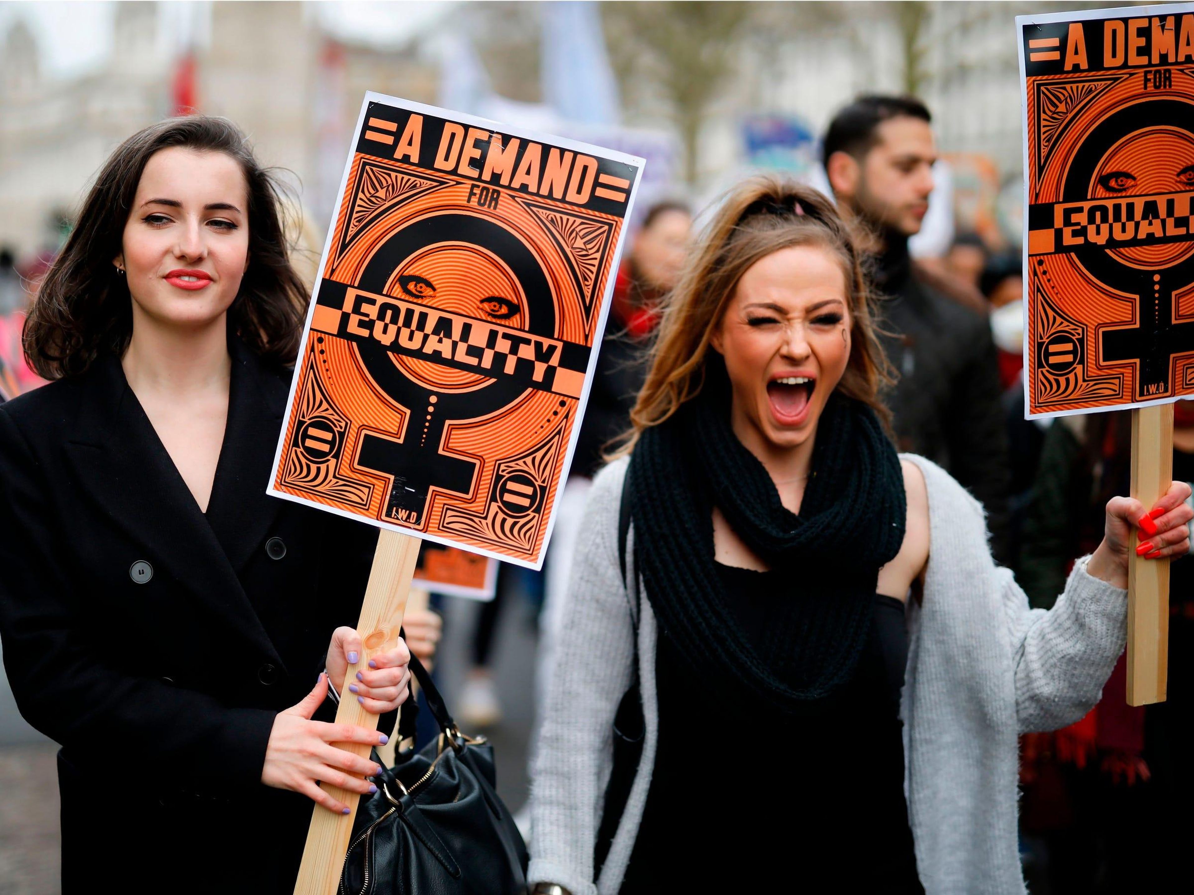 Marchers in London hold signs with messages of gender equality at a "March 4 Women" parade.