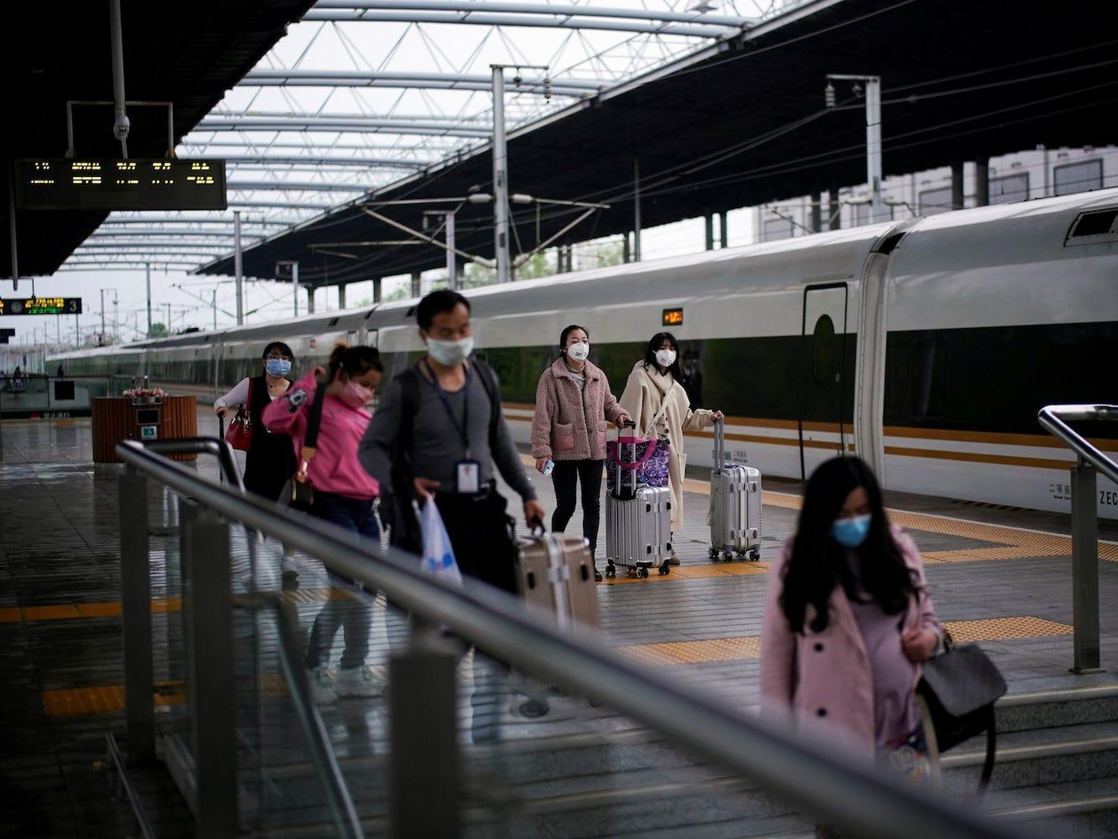 Pasajeros que llevan mascarillas viajan con sus maletas en una estación de tren en Xianning, provincia de Hubei, el 25 de marzo de 2020.