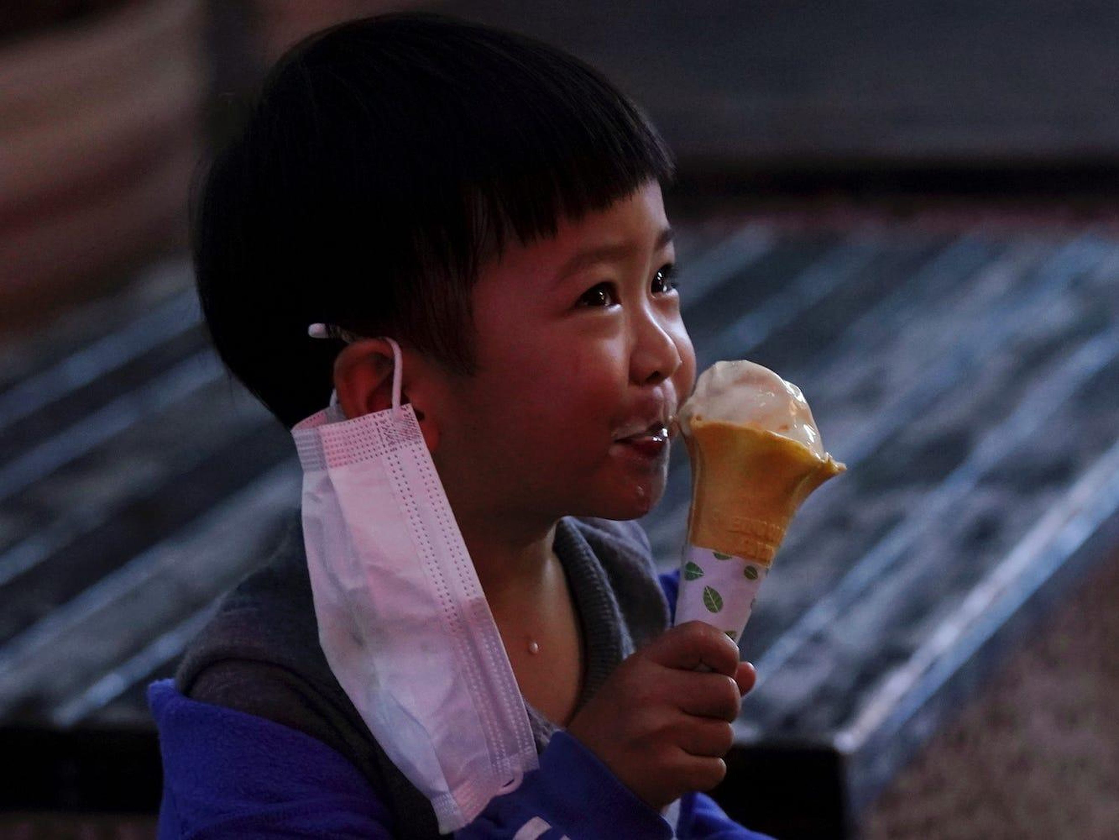 Un niño con una mascariila se toma un helado en el primer día de apertura de Xianning, el 25 de marzo de 2020.