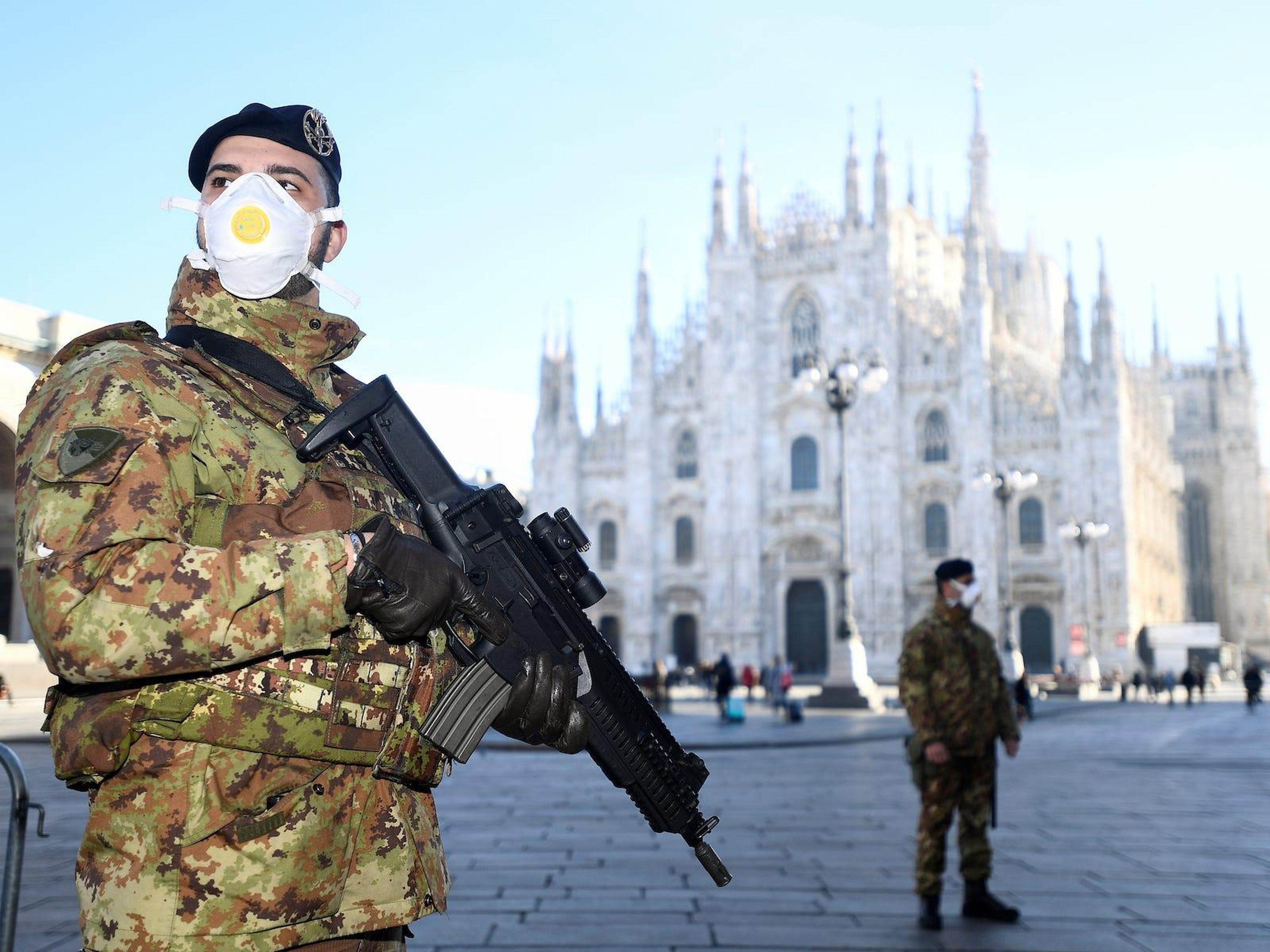 Oficiales militares con mascarilla se encuentran fuera de la catedral del Duomo, cerrada por las autoridades debido a un brote de coronavirus, en Milán, Italia, el 24 de febrero de 2020.
