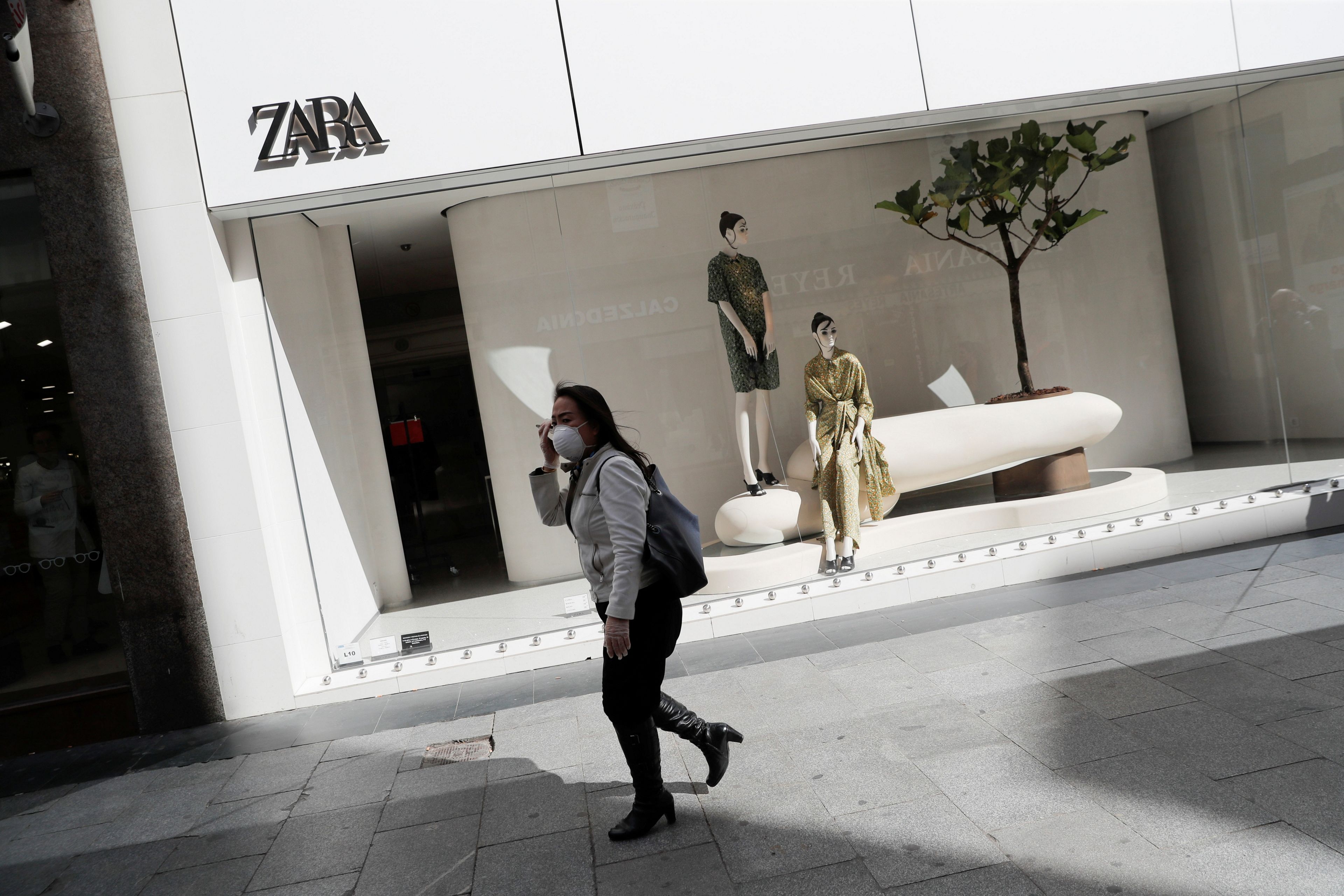 Una mujer con mascarilla camina delante de una tienda de Zara en Madrid durante el periodo de confinamiento.