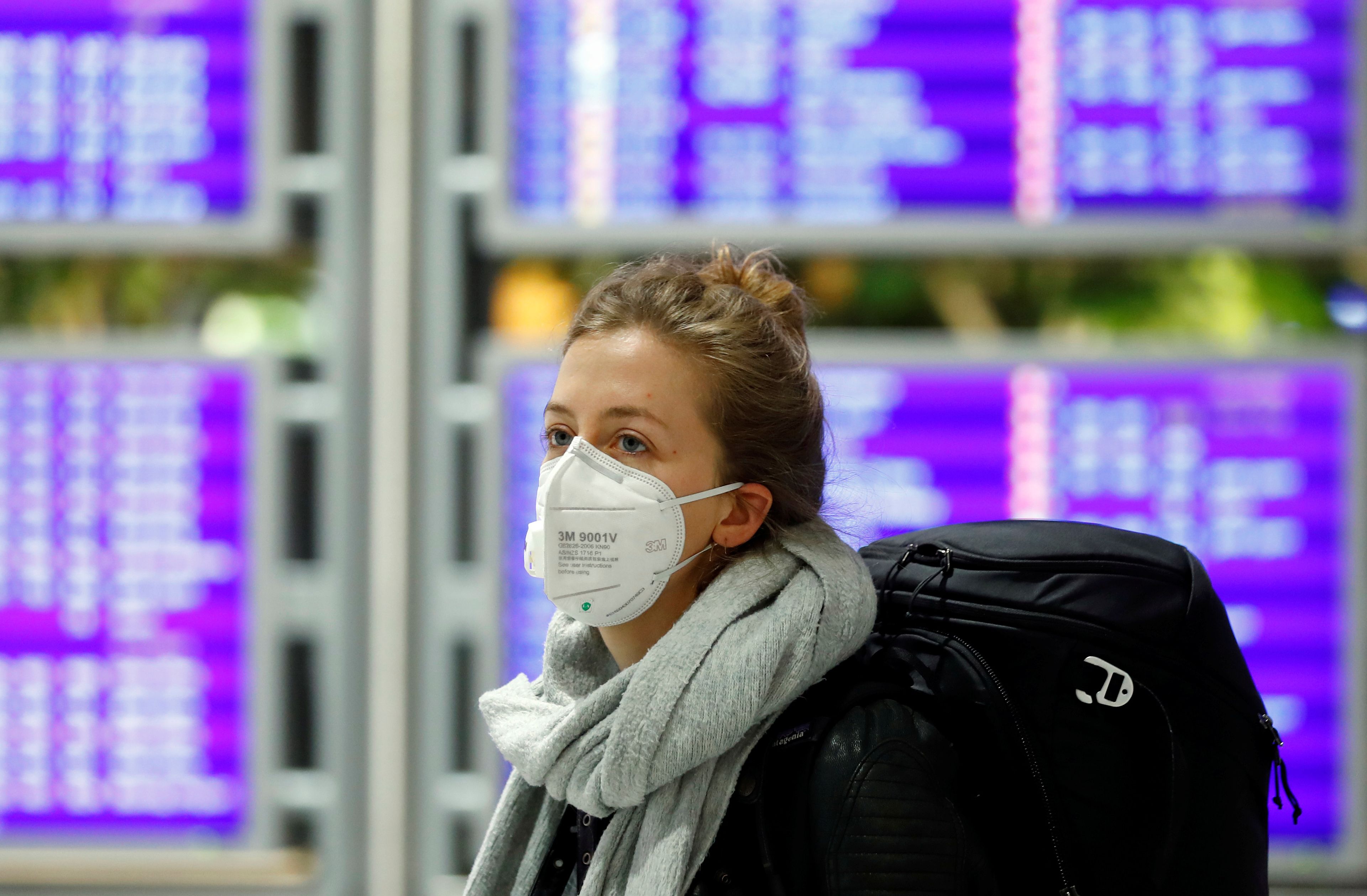 Una mujer con mascarilla por el coronavirus en un aeropuerto.